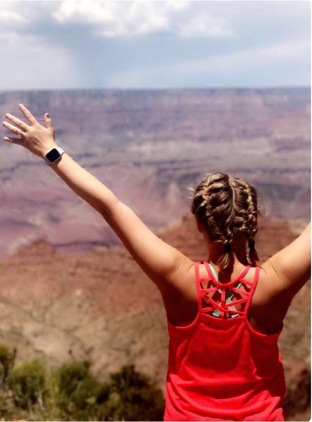 Shot of daughter from back with arms outstretched, looking out into a canyon.