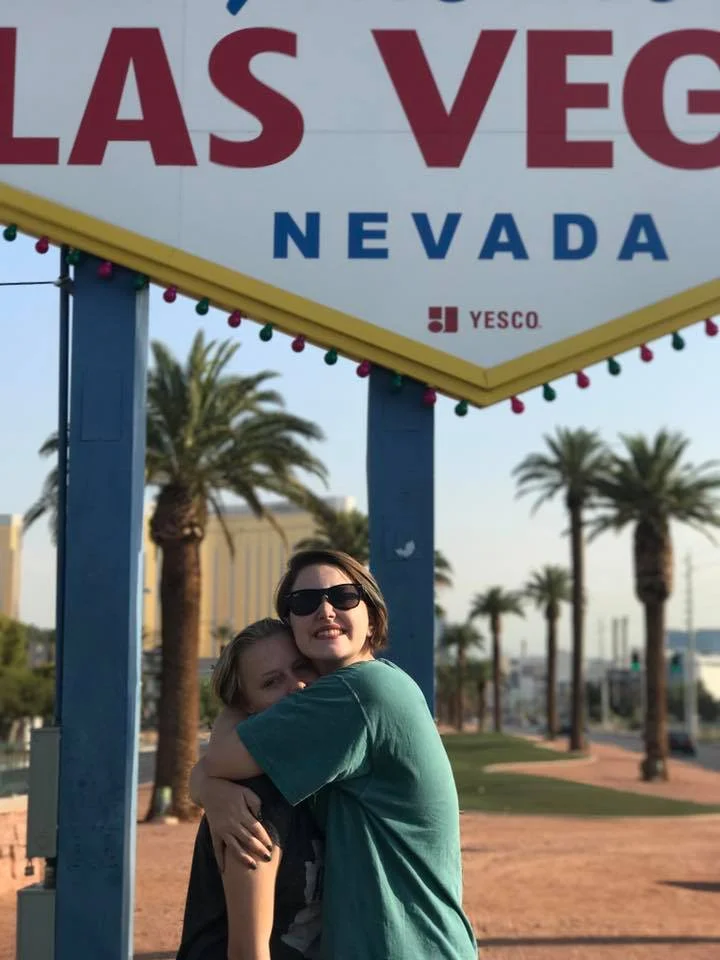 Two daughters hugging under the Las Vegas sign.