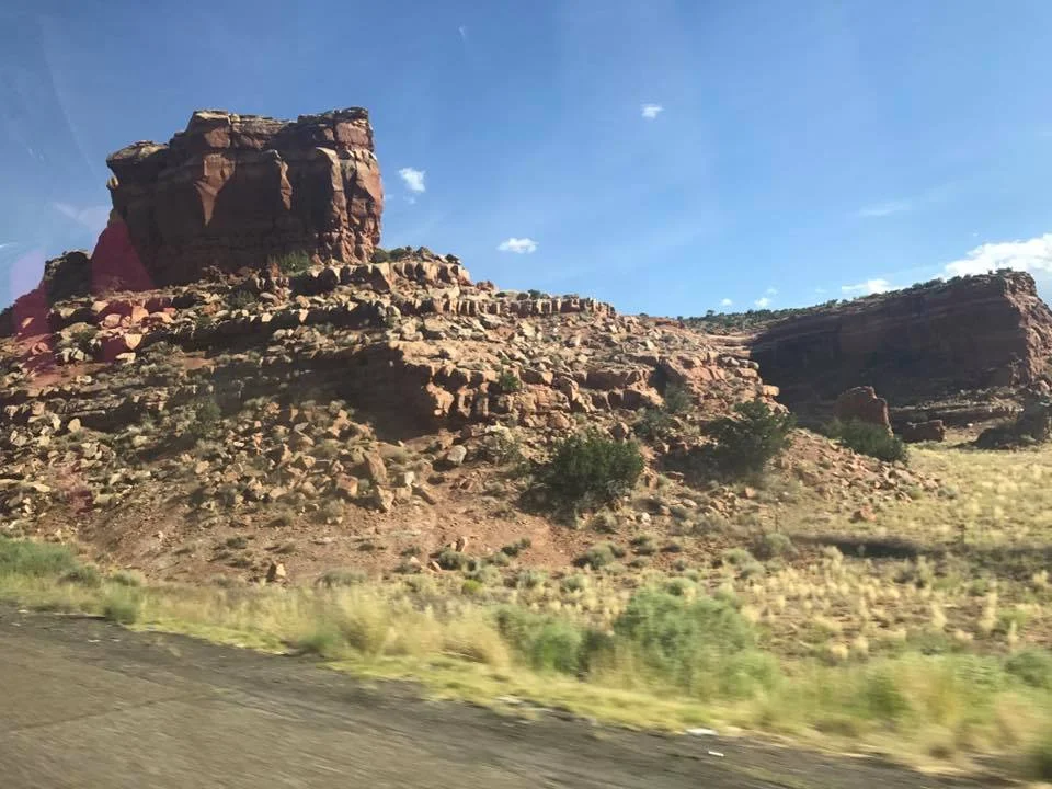 Shot from car of desert rock formations.