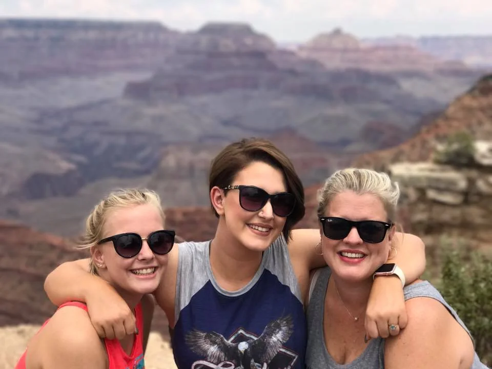 Mother and two daughters with canyon and mountains in the background.