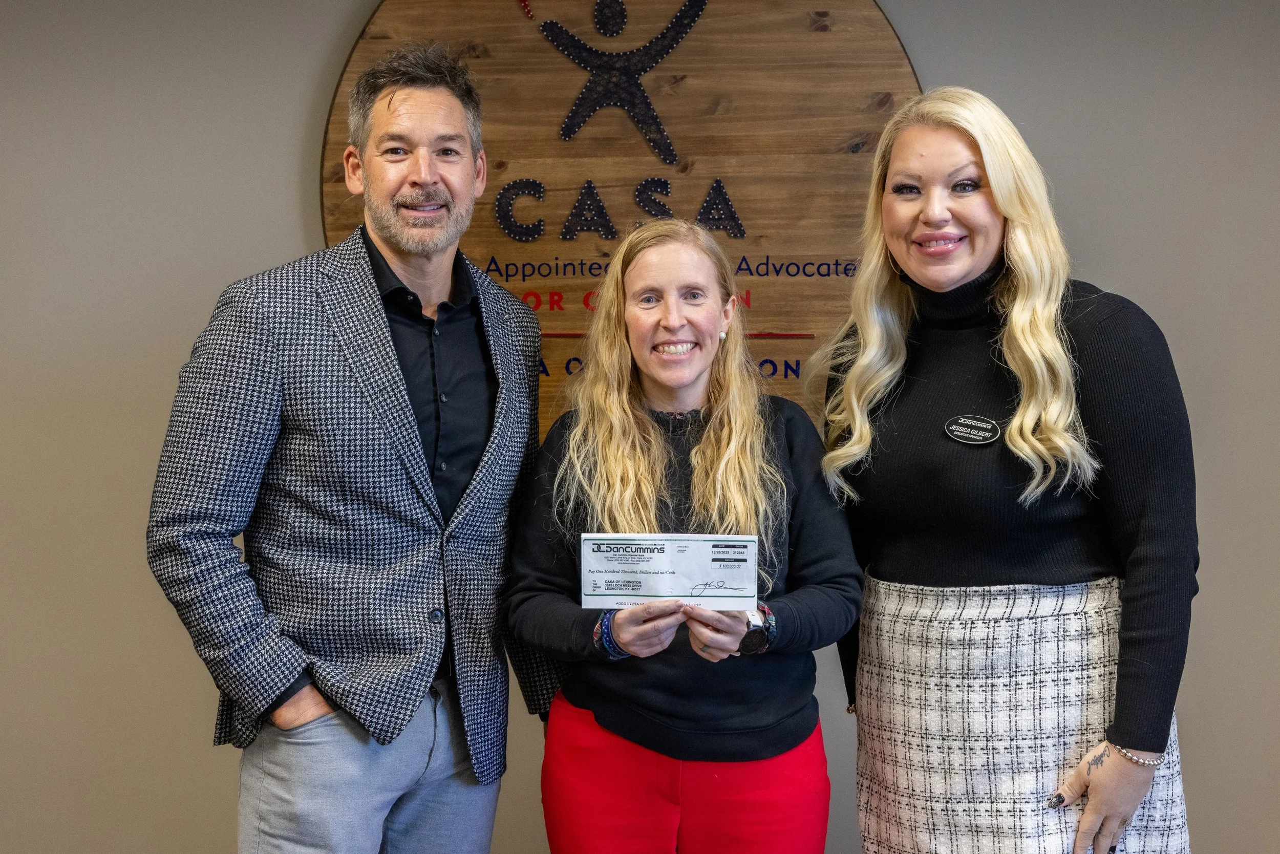Josh Cummins, left, and Jessica Gilbert, right, both with Dan Cummins Auto Group, present a check for $100,000 to CASA of Lexington Executive Director Melynda Jamison on Jan. 30.
