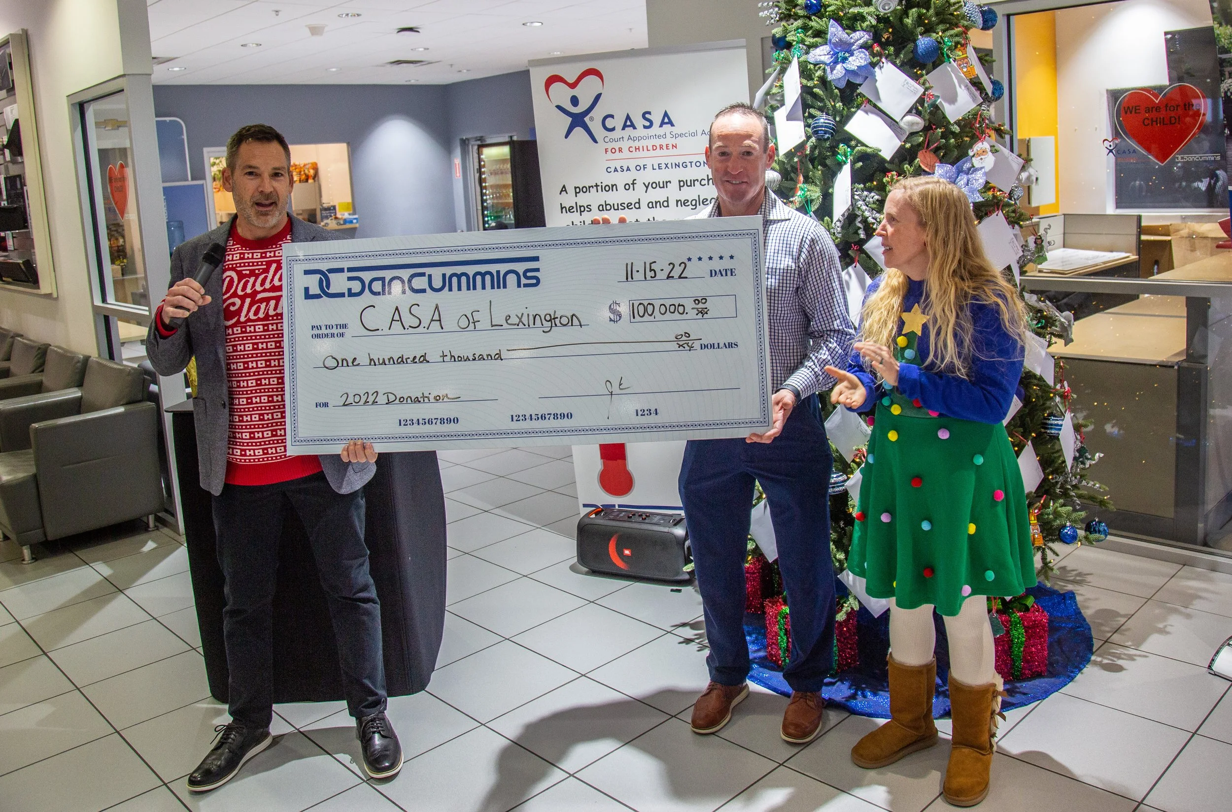 From left, Josh and Dusty Cummins present CASA of Lexington Executive Director Melynda Jamison with a $100,000 donation, taken from the sales of vehicles at the Dan Cummins family of dealerships in 2022.