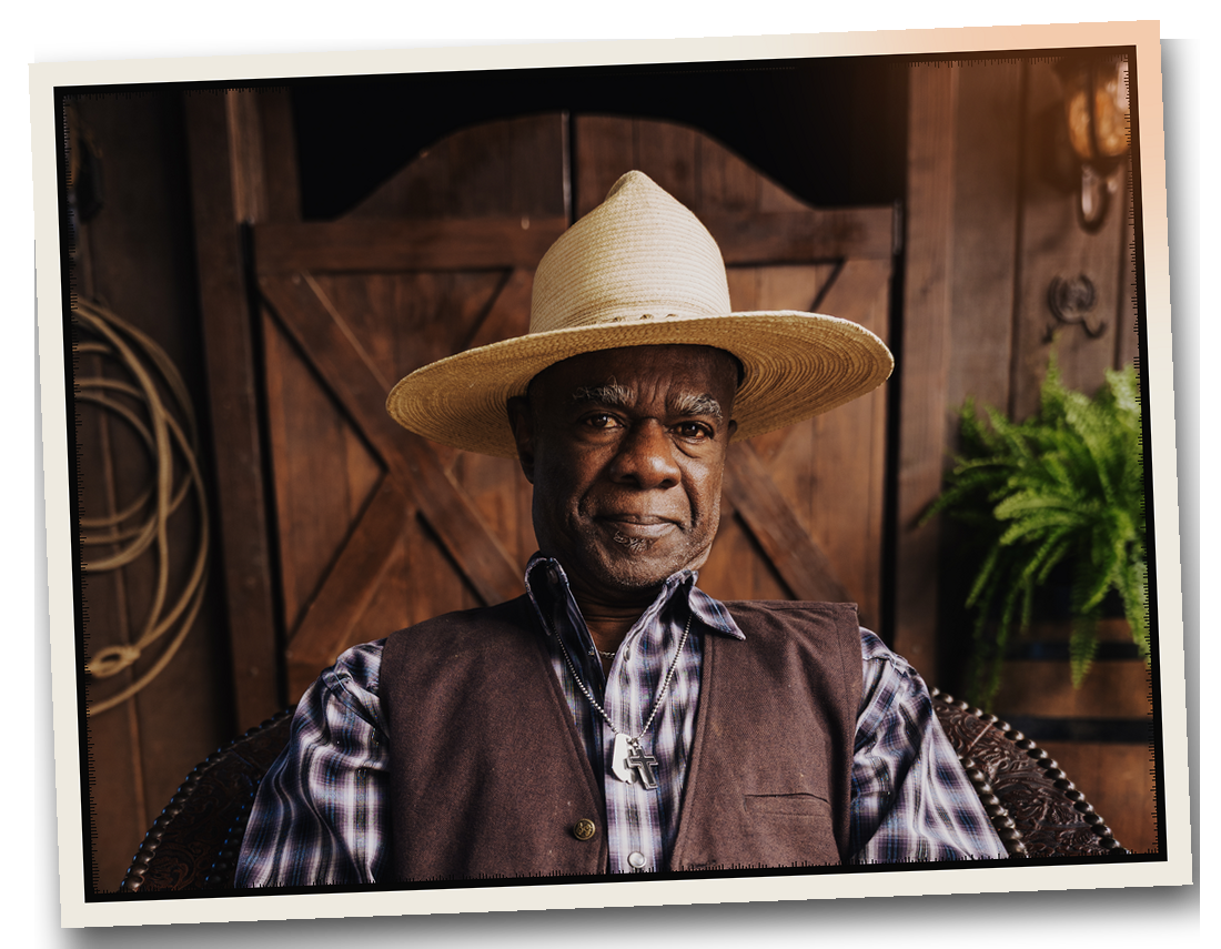 An older cowboy in a straw hat and vest, from High Horse on Peacock.