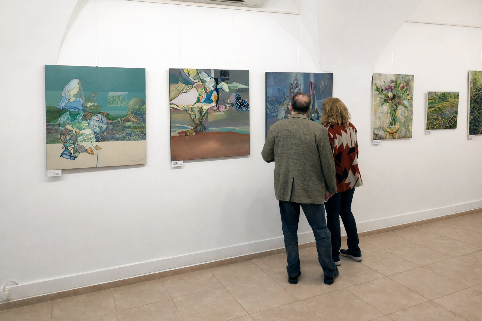 Two visitors viewing Alexey Adonin’s paintings at Jerusalem Rainbow: Magic of Color, Skizza Gallery, Jerusalem, 2019.