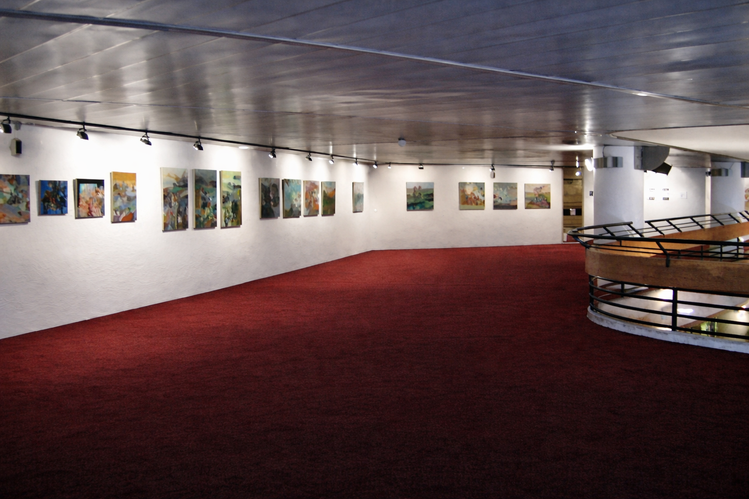 Wide view of Alexey Adonin’s solo exhibition Reflection, with paintings lining the curved gallery wall above red carpeting, Jerusalem Theater, 2011.