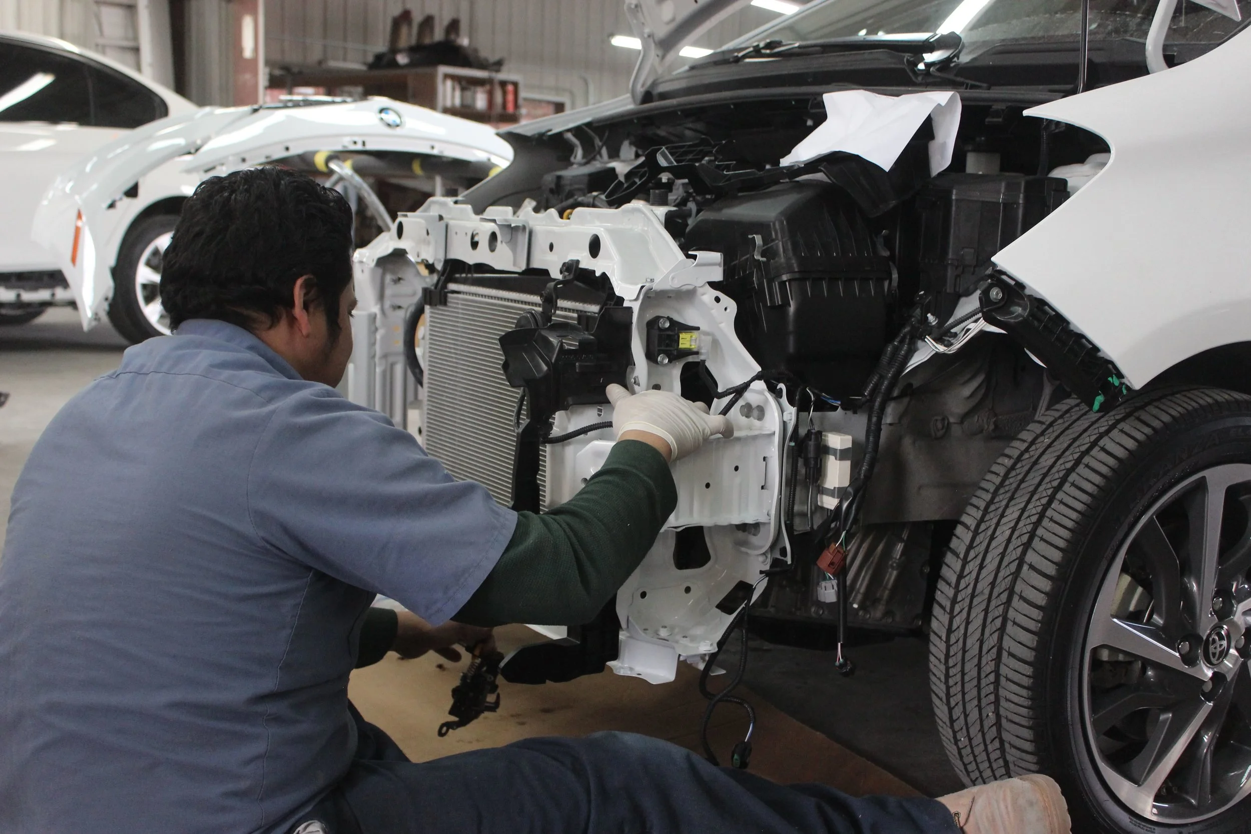 Mechanic at Cho’s auto body shop is repairing a damaged car