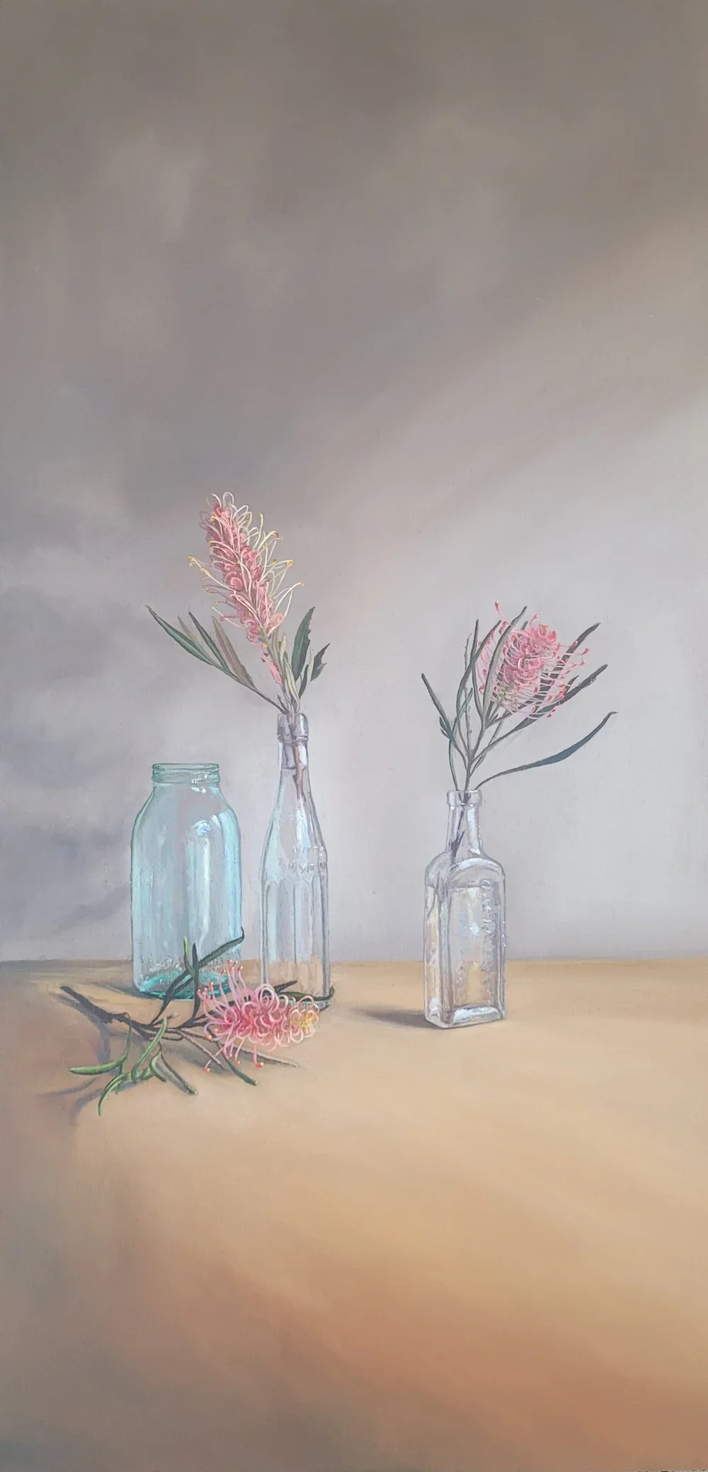 Love Conquers All fine art print by Heidi Emma featuring pink Australian grevilleas arranged in vintage glass bottles with one flower resting on a wooden table.