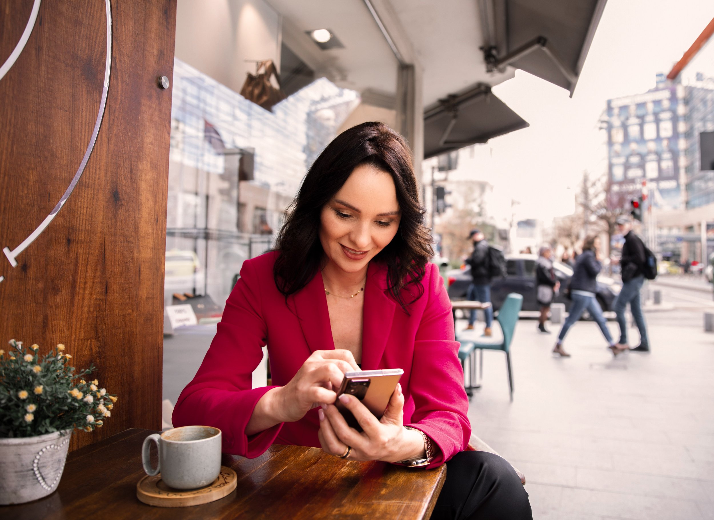 Woman sitting at a table on her digital device.