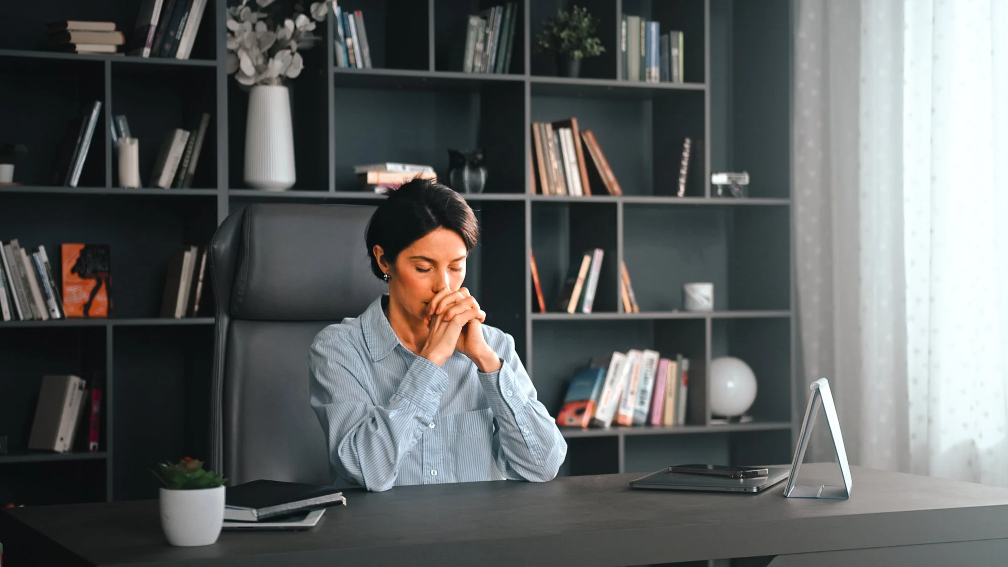 woman praying while sitting at her desk