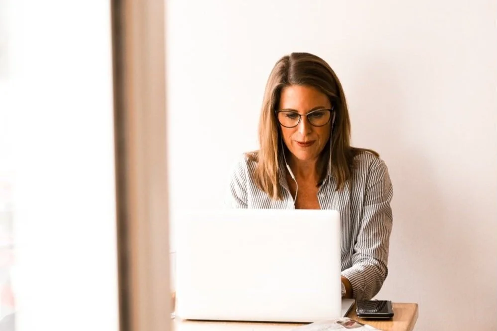Woman in glasses working on a laptop at a desk
