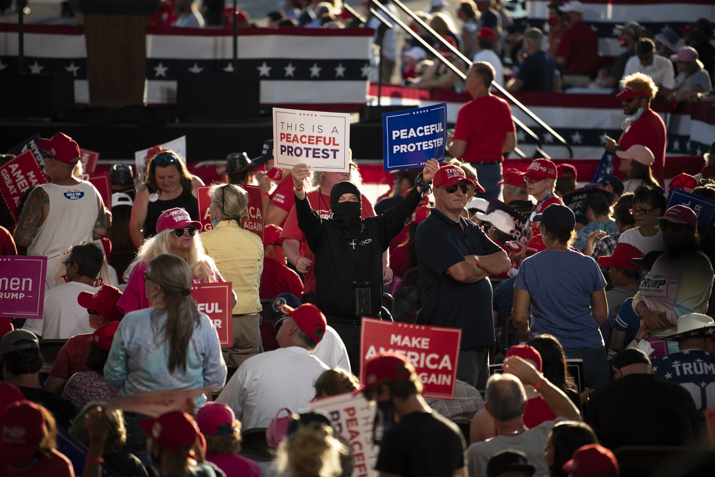  A Trump supporter holds “Peaceful protester” signs while waiting for President Trump to arrive at the rally in Londonderry, N.H., on Aug. 28, 2020. 