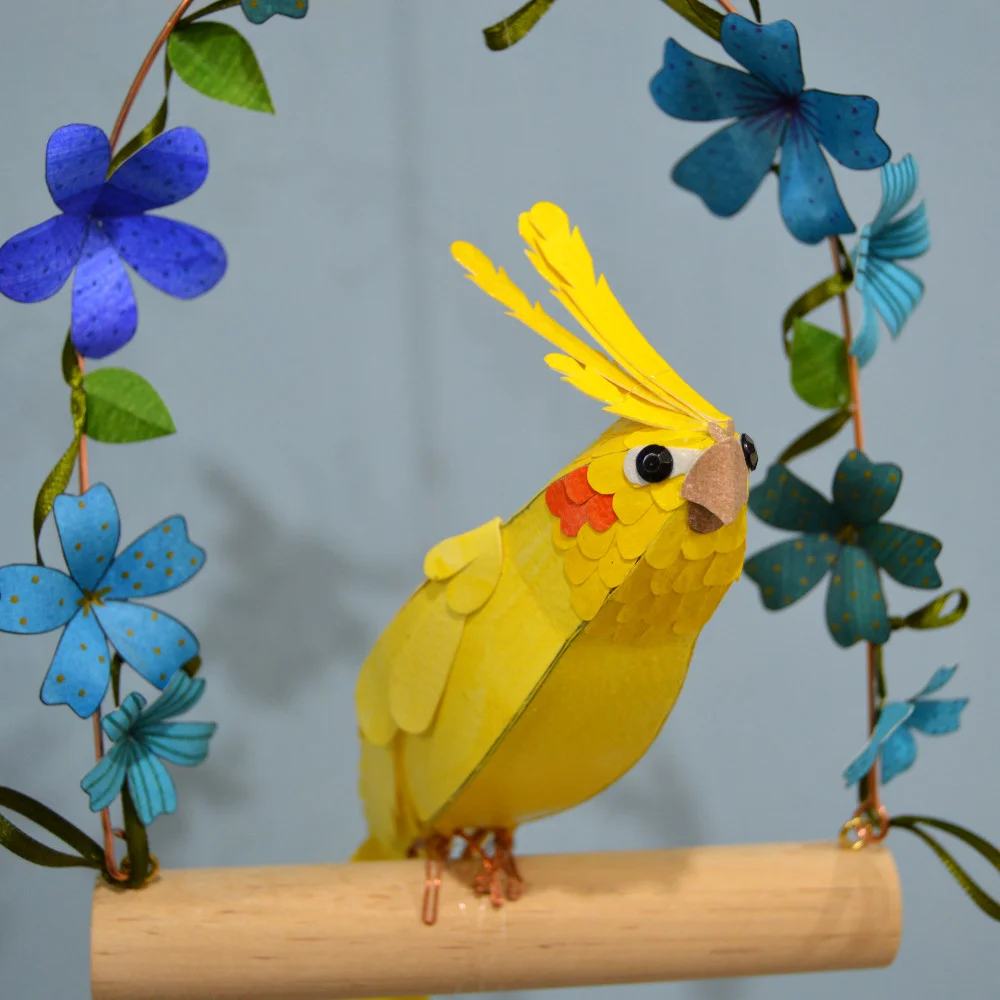 Happy the cockatiel on a swing with blue flowers