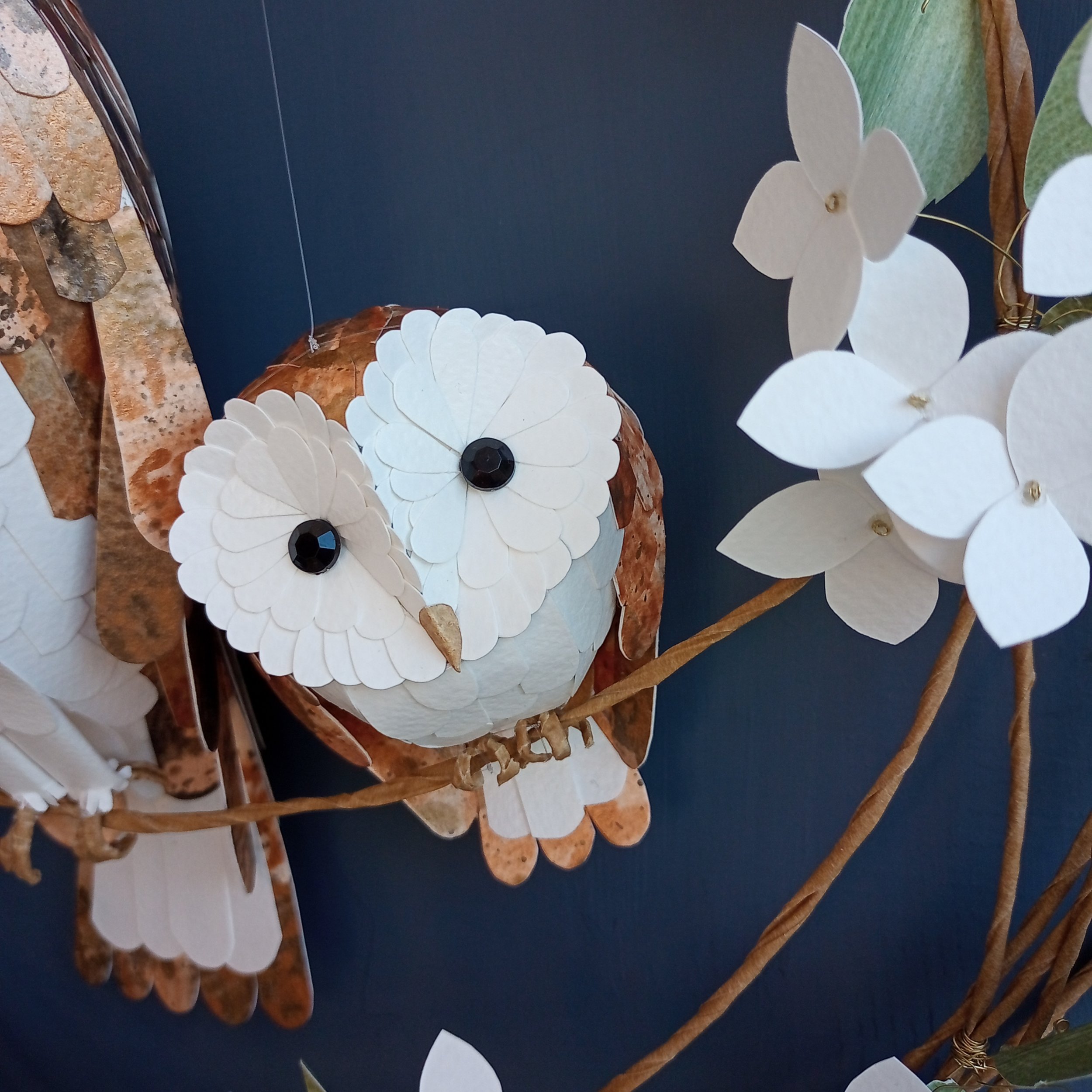 a close up of a baby barn owl sculpture, made from hand printed papers by paper artist Kaper.