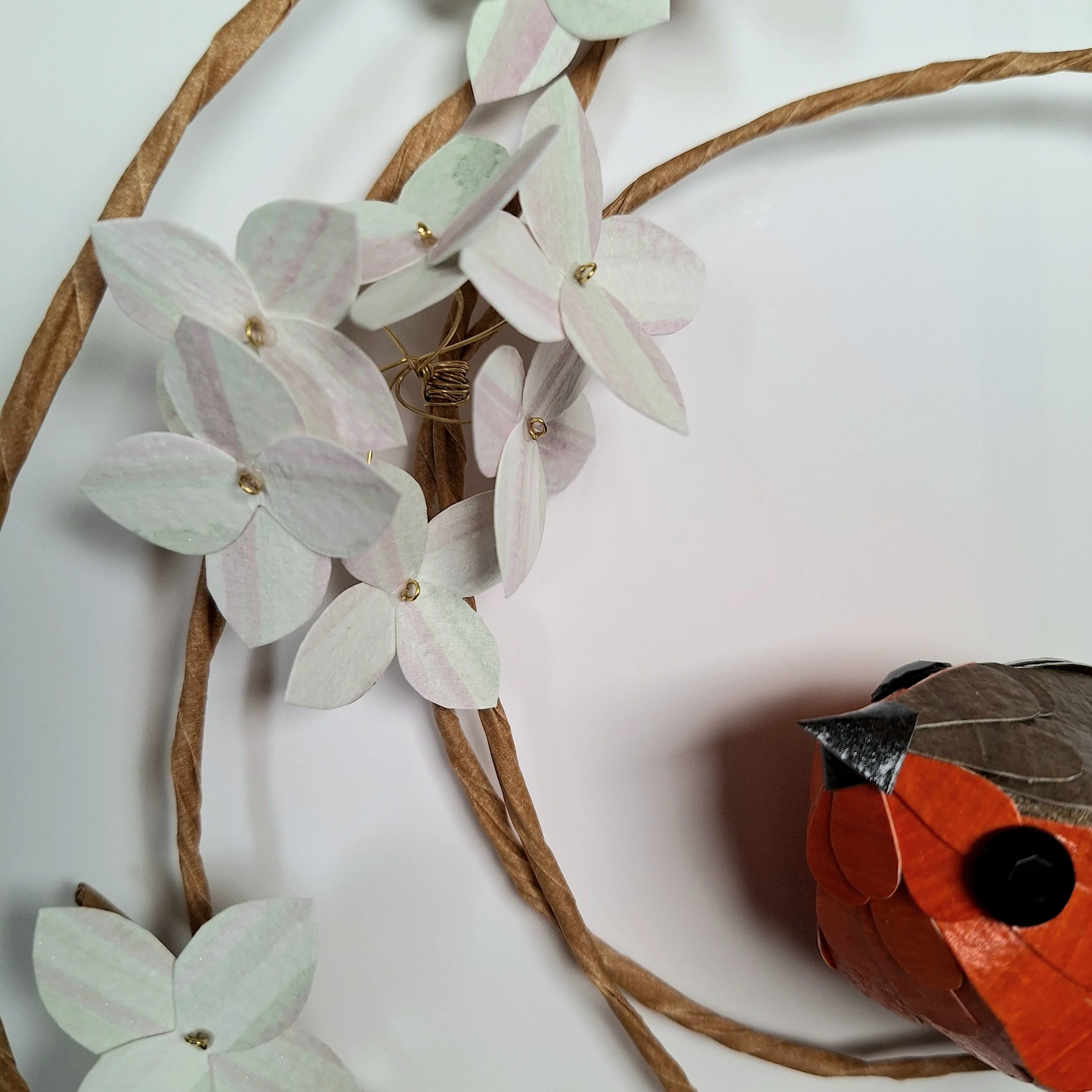 A close up of the hydrangea flowers that adorn the wreath sculpture. They are palest green, with a tiny hint of pale pink adding a bit of colour and pattern to the individual blooms.