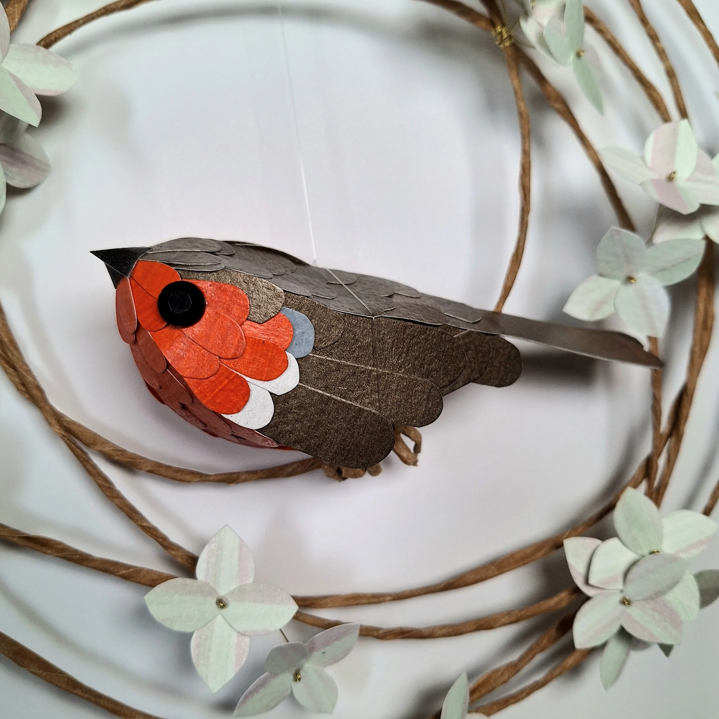 A close up of the robin red breast sculpture, where you can see his hand-cut paper feathers covering his body.