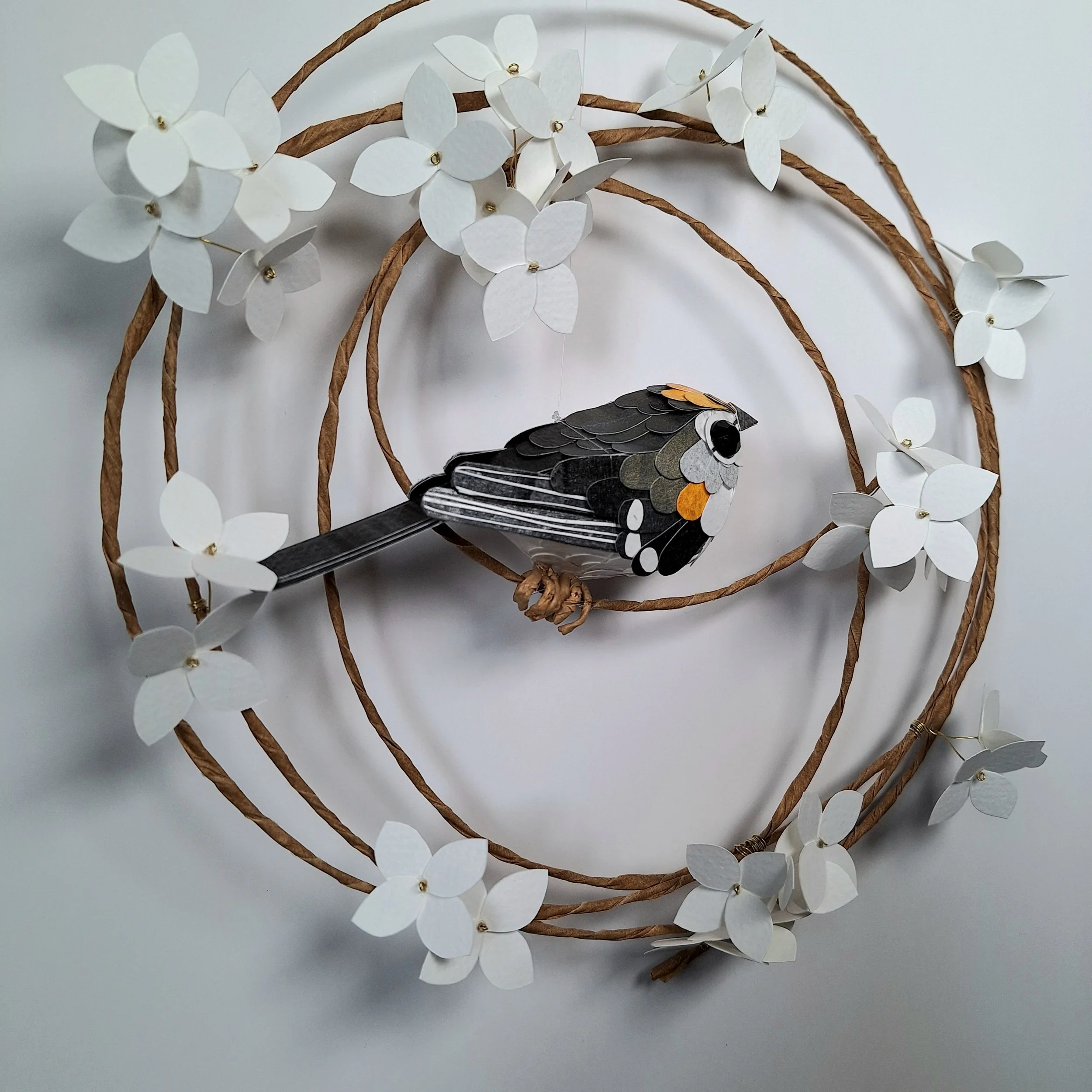 Side back view of the bird sculpture. You can see his wing and tail feather details. His tail is dark and his wings have delicate white stripes.