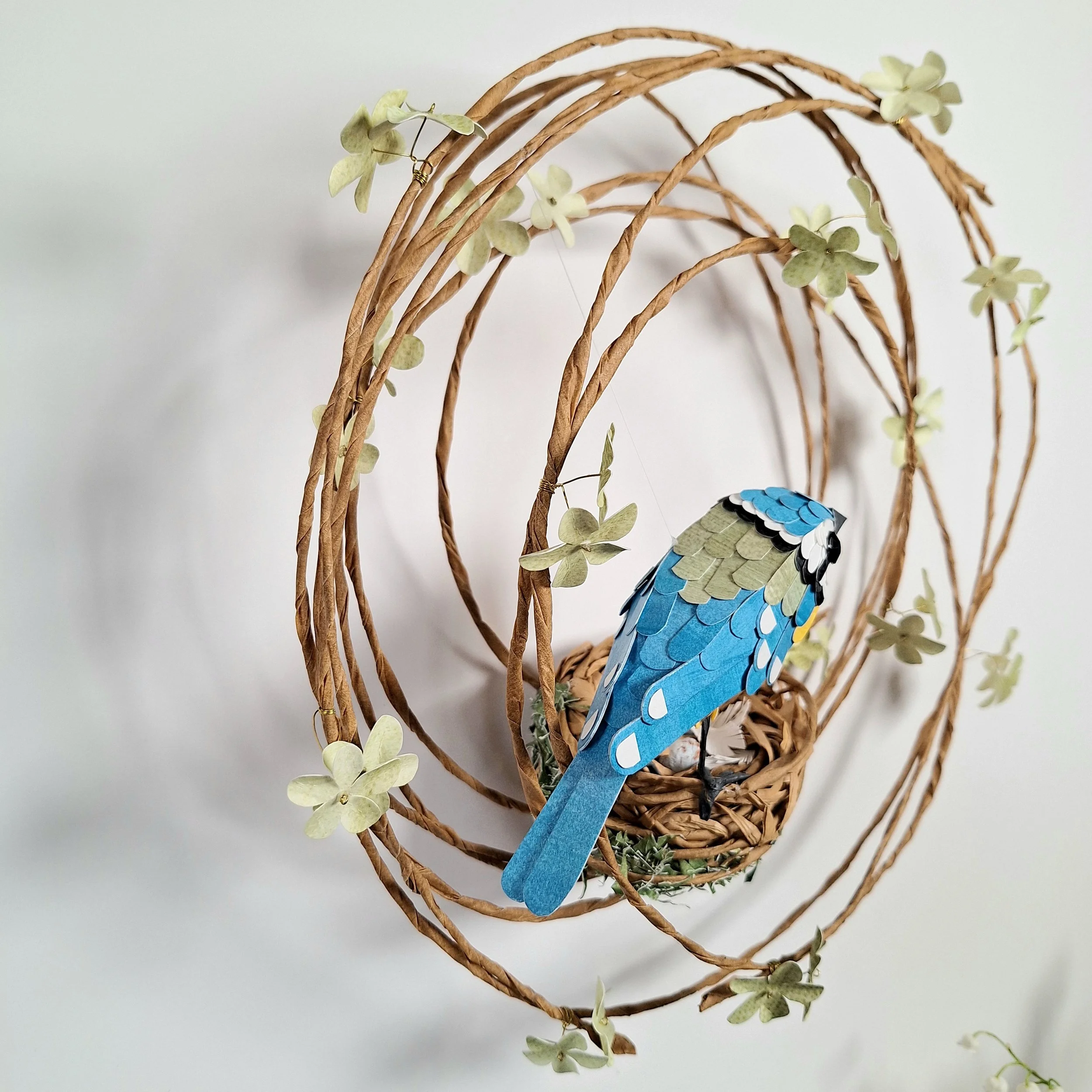 side view of the bird sculpture. From this angle you can see the wing and tail feathers and the green flowers on the wreath.