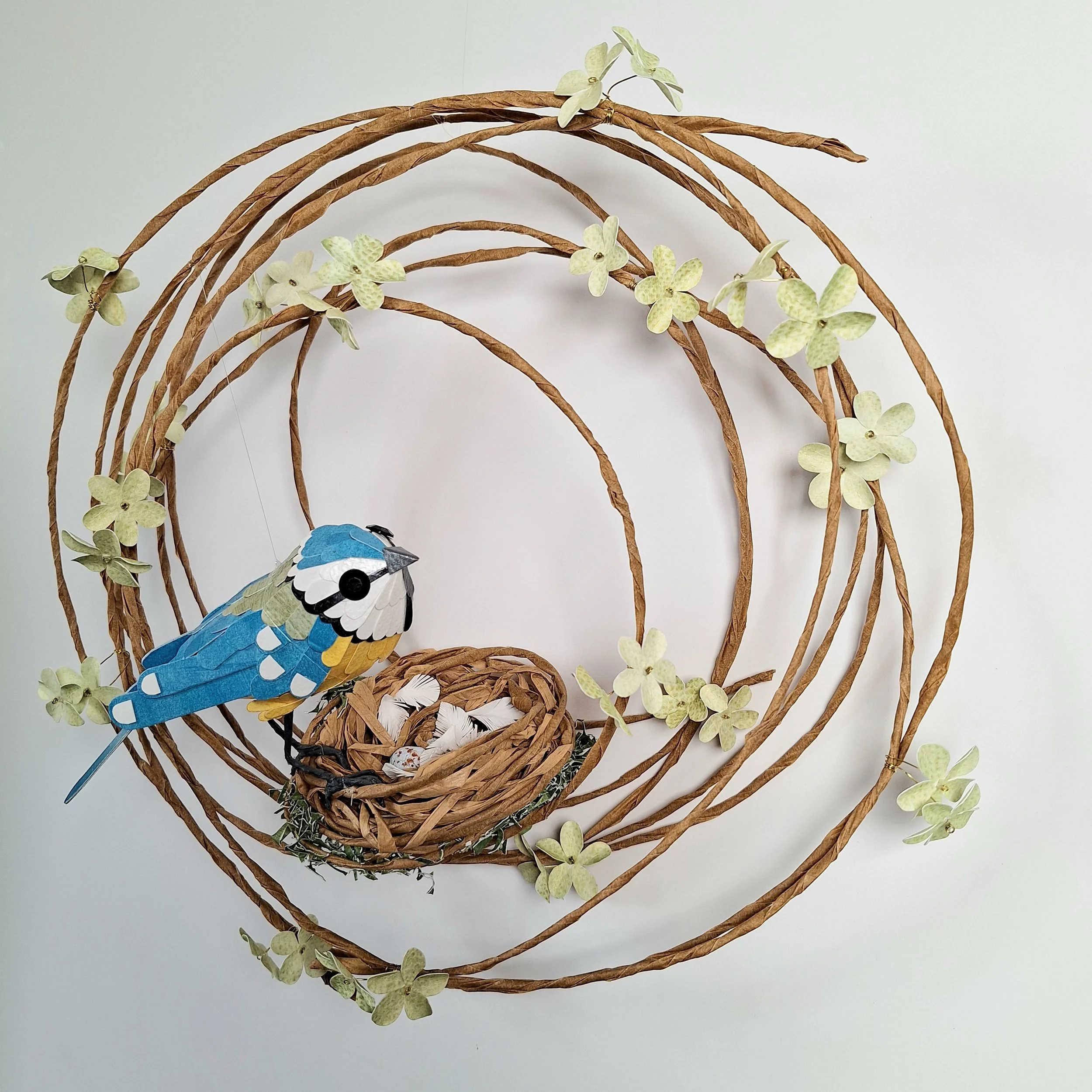 Handmade Floral wreath feayuring a sculpture of a blue tit sat on a nest with three eggs.