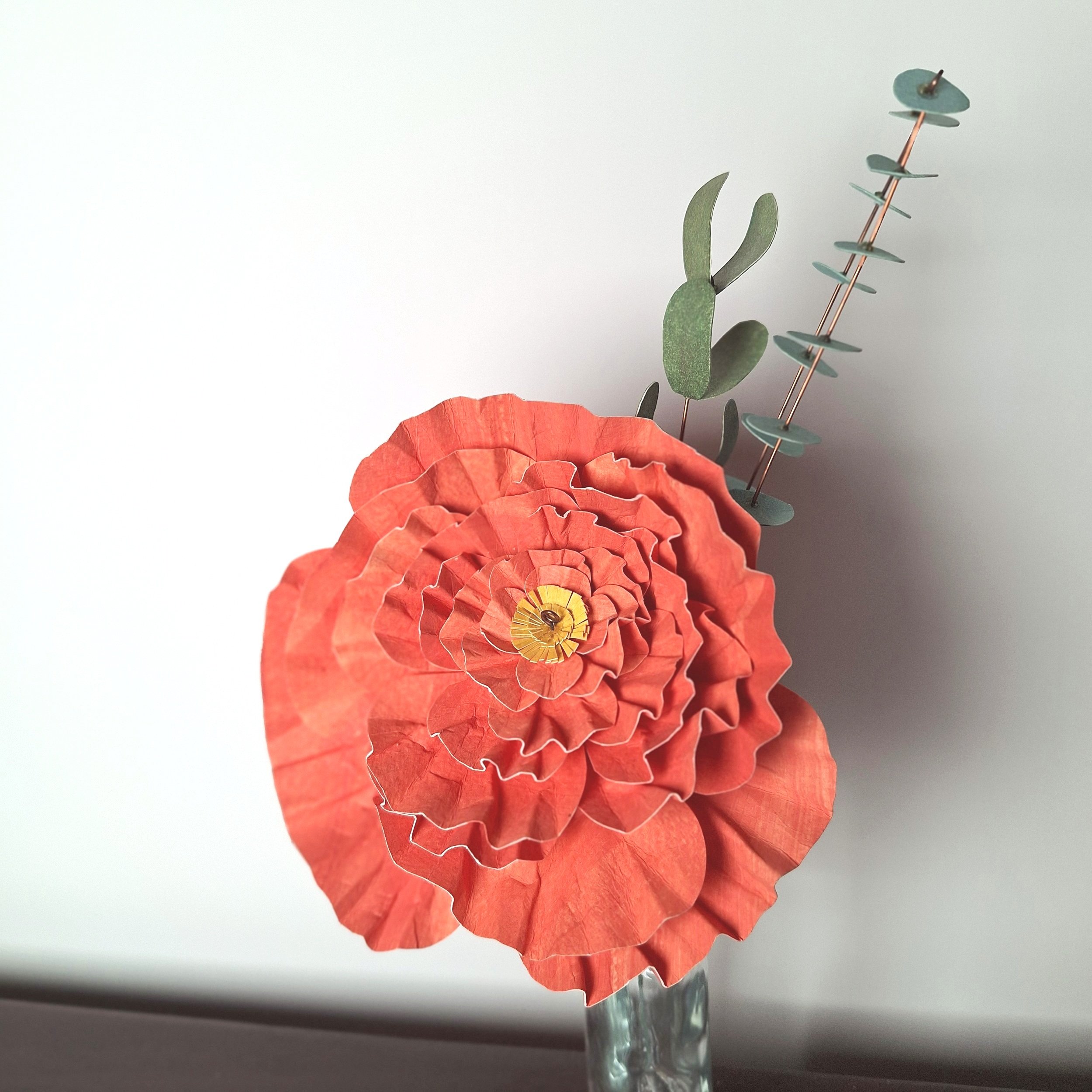 close up of a handmade paper sculpture of a coral peony everlasting flower