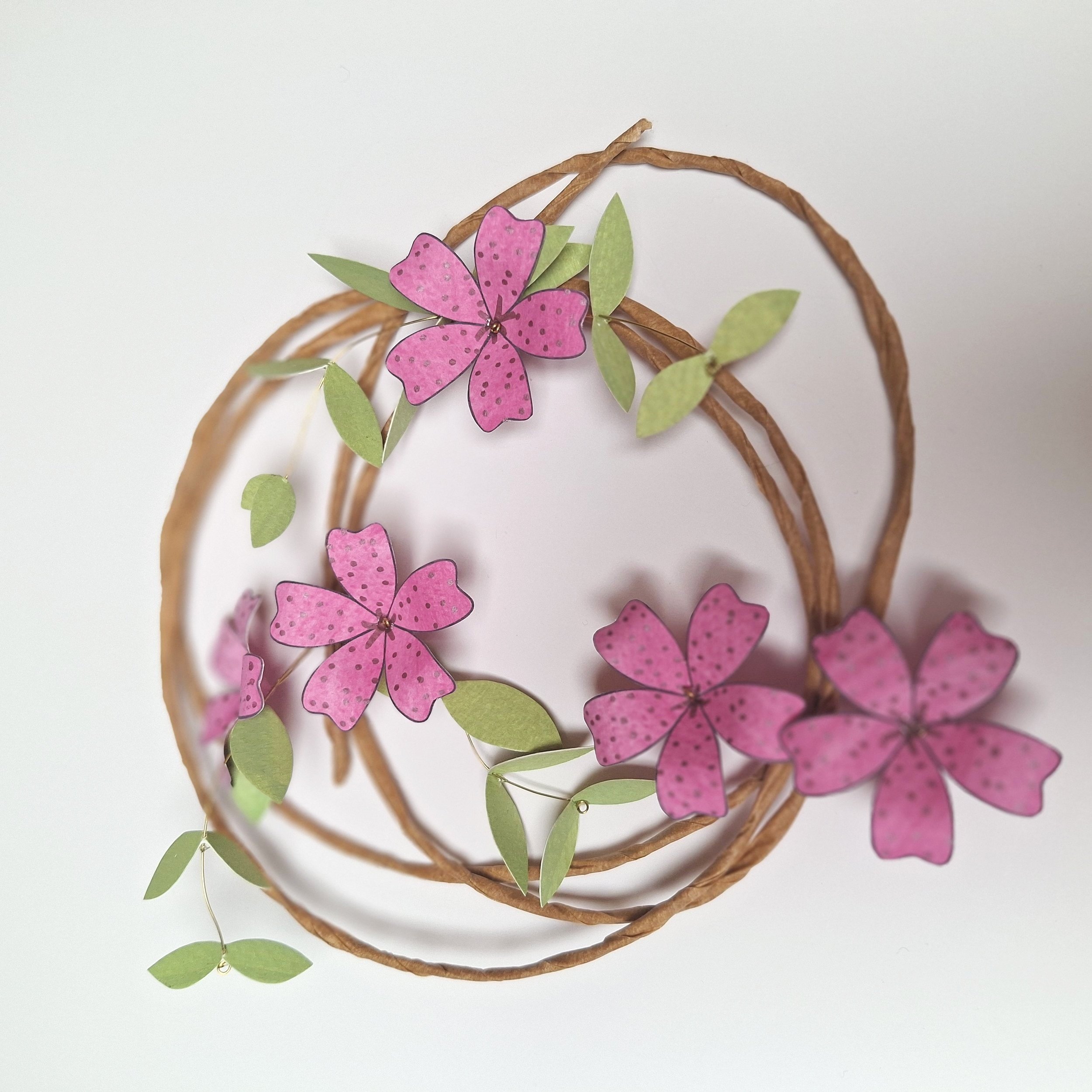 A handmade paper flower wreath, featuring bright pink flowers
