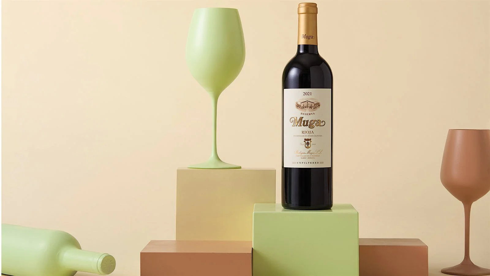 Bodegas Muga Rioja Reserva 2021 displayed in bottle beside an opaque wine glass, colored pastel green