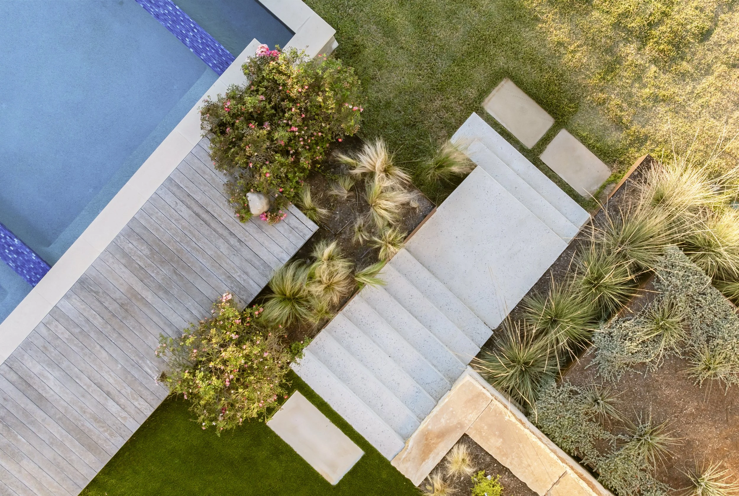 Aerial view of a modern outdoor space with stairs, greenery, and a swimming pool.