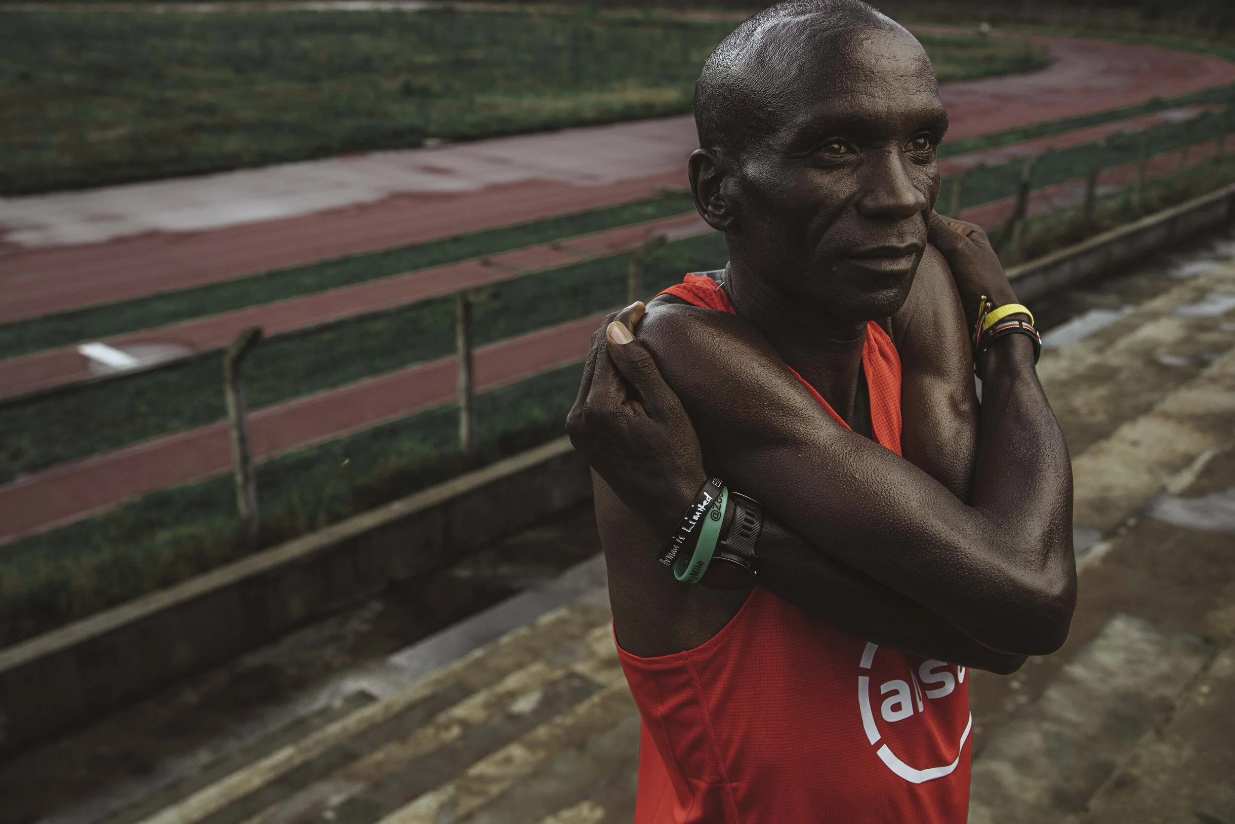 Eliud Kipchoge Runner in red top stretching arms at outdoor track