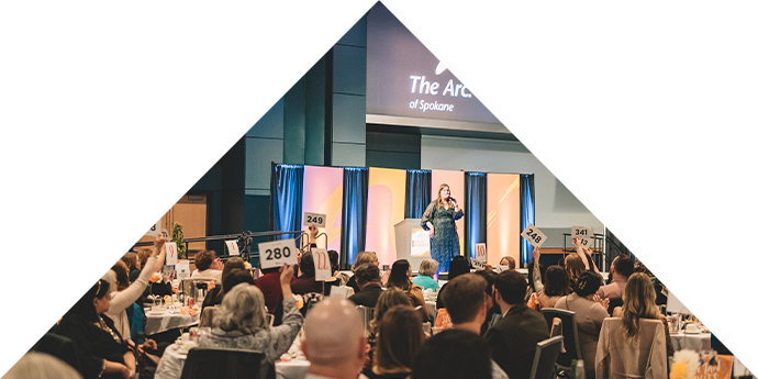 An image of the crowd from Rock the Runway. Several attendees hold up paddles while bidding on prizes during the live auction
