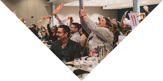 Image of atendees from Rock the Runway waiving flags and taking pictures while they excitedly watch the runway models