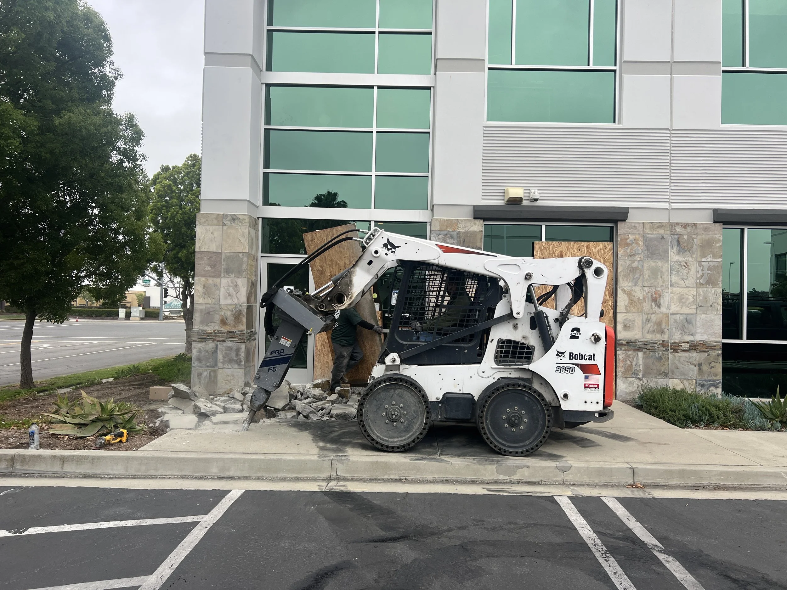 bobcat breaking concrete sidewalk commercial building in Ontario 