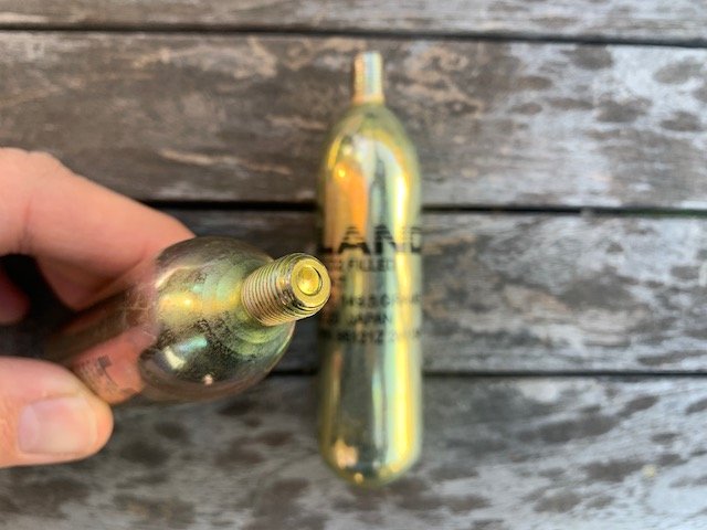 Hand holding Leland cartridges to show the new unpunctured top of the co2 cartridge used for life vest ifnlation.jpeg
