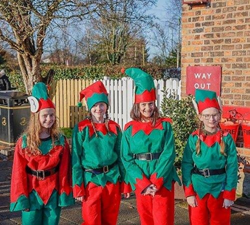 Four elves from Ellesmere Port Church of England College support the Santa's Grotto event by Friends of Hadlow Road Station