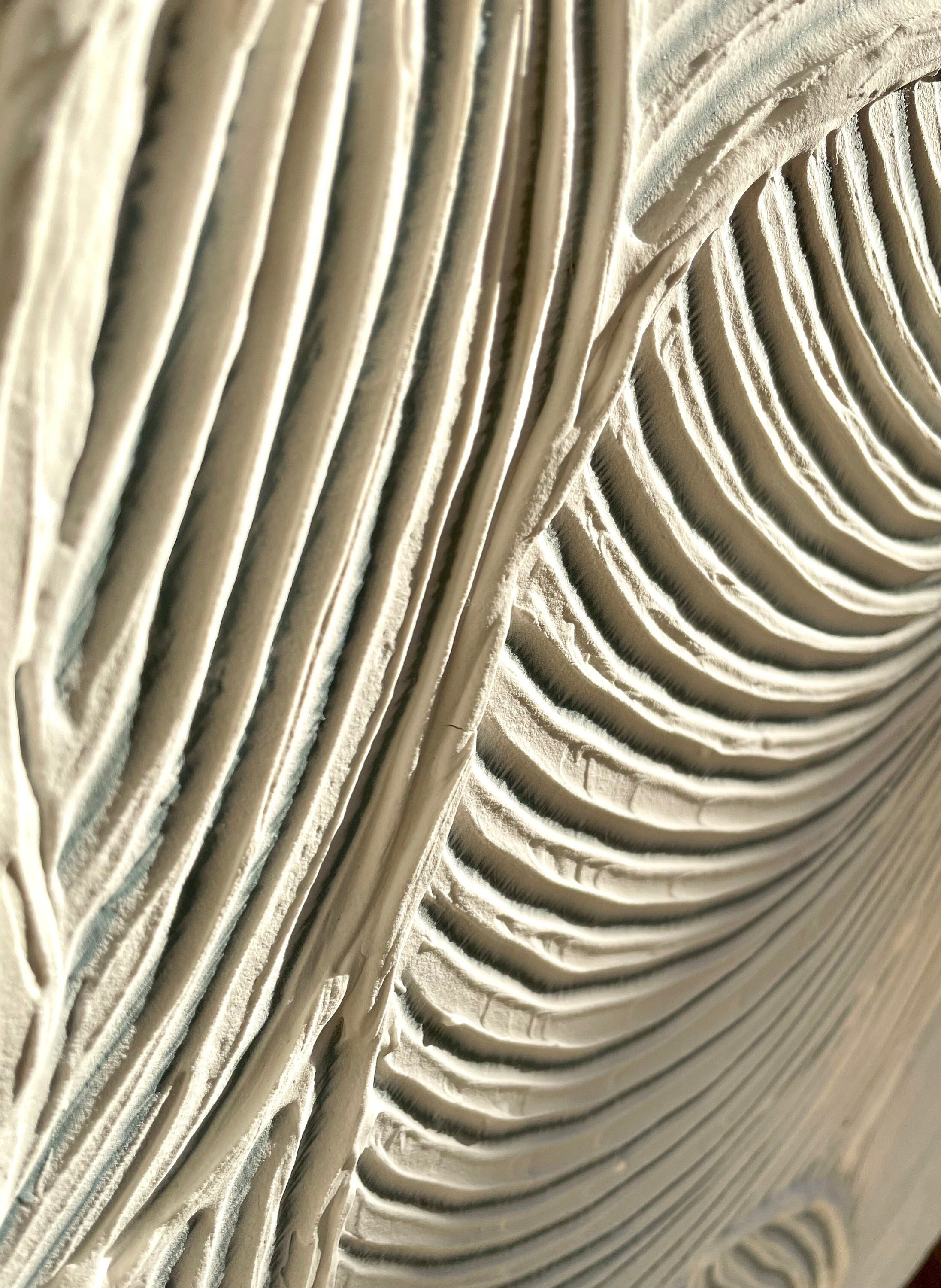 Close-up of intricate textured art on a light-colored, fan-like surface, resembling ripples, reminiscent of a custom-made sideboards exquisite craftsmanship.