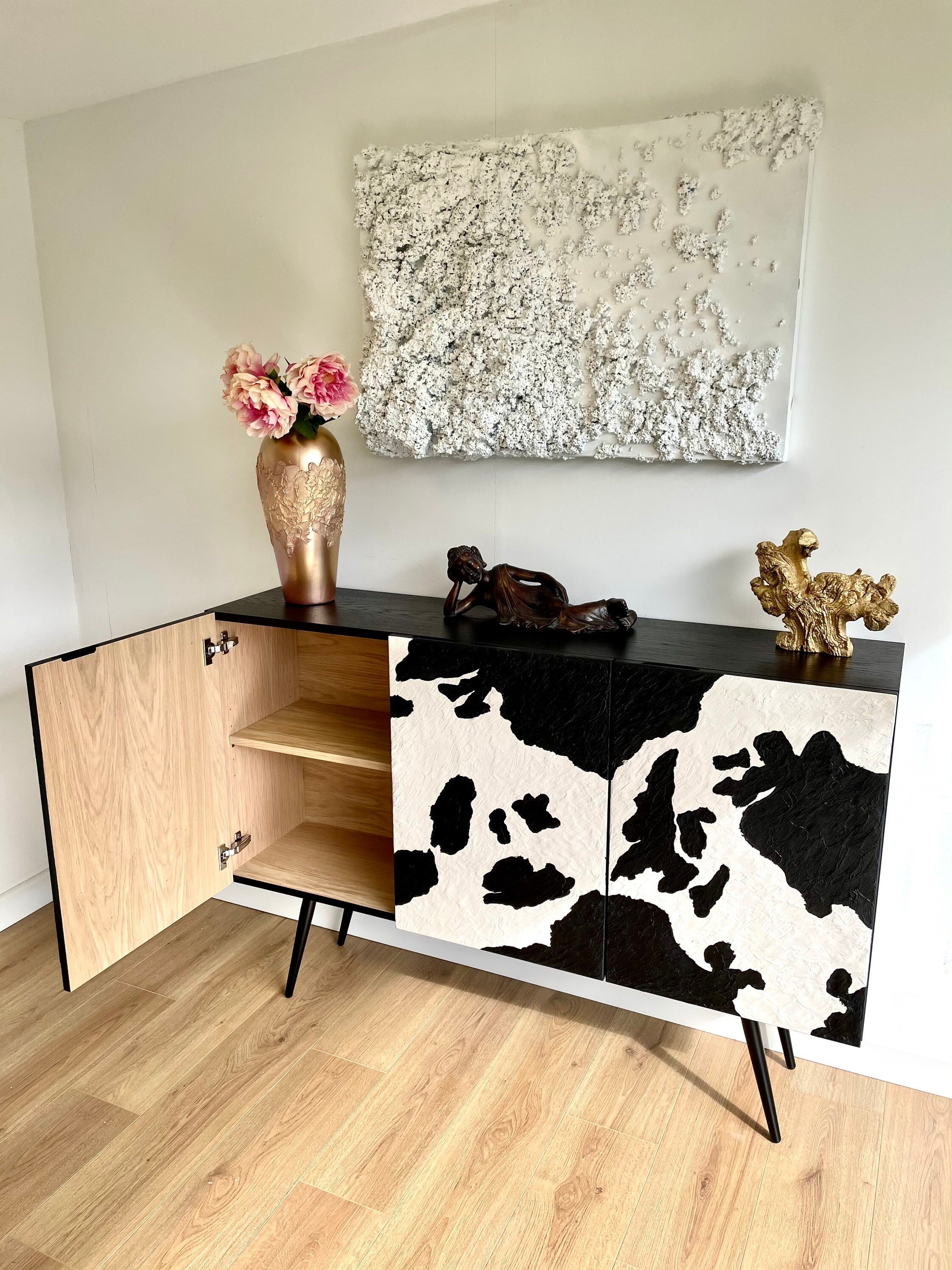 A bespoke sideboard with open wooden doors features a black and white cowhide pattern. Interior is natural Oak finish.