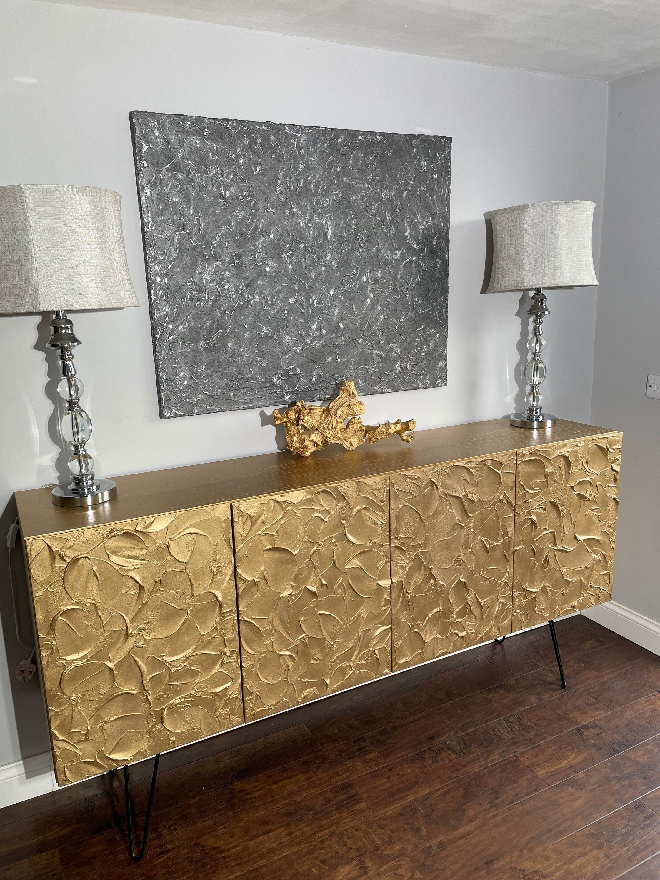A textured golden cabinet with floral patterns stands against a light gray wall, epitomizing bespoke furniture.