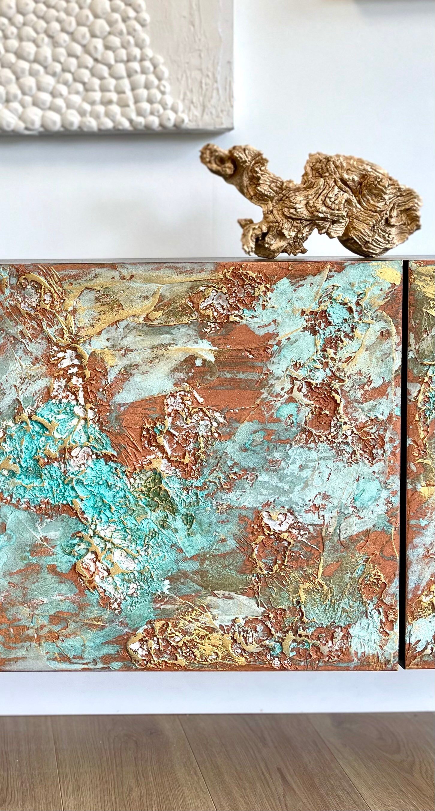Close-up of a custom-made sideboard featuring swirling patterns in turquoise, gold, and brown, resembling a mixed media artwork.