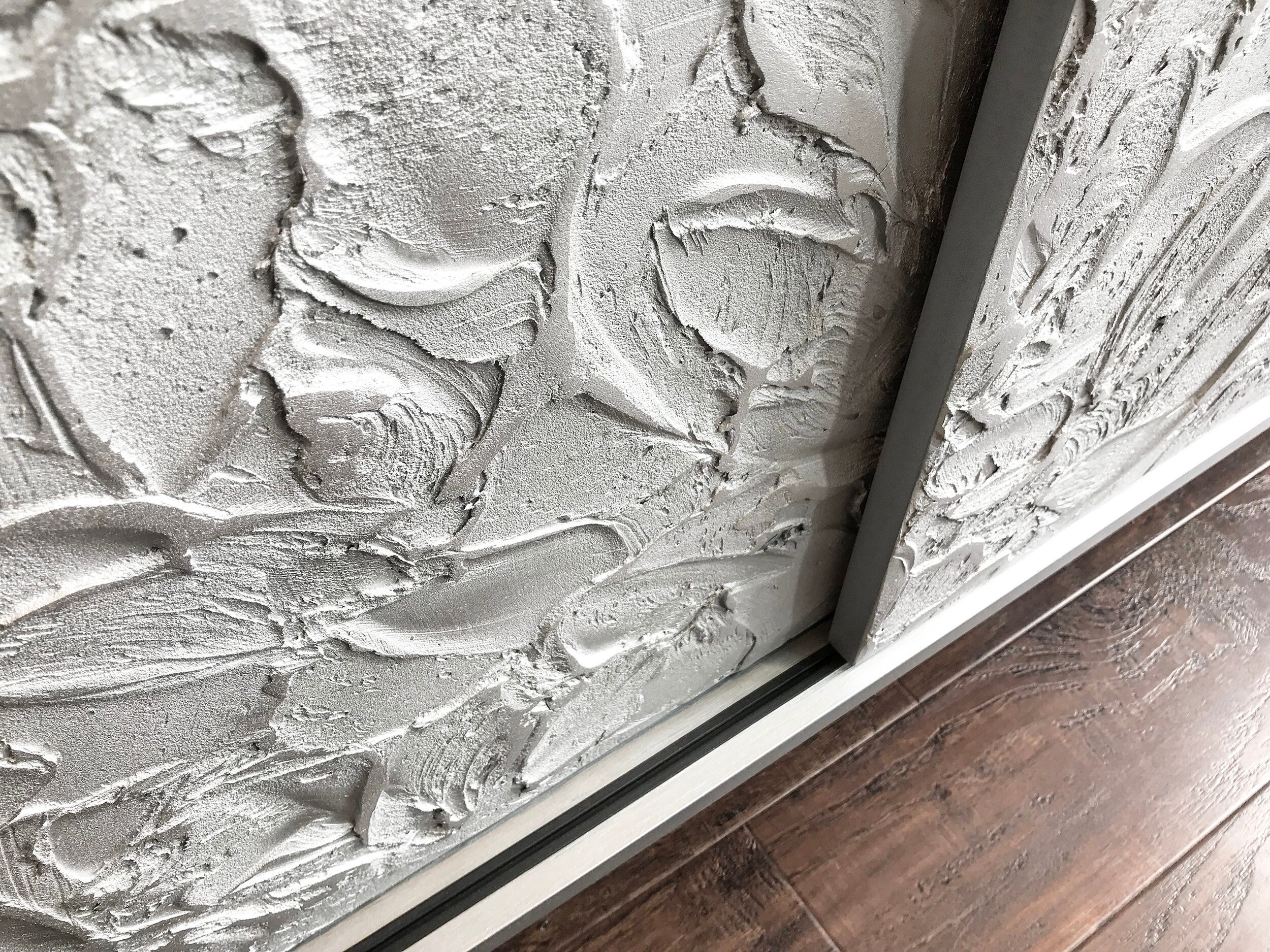 Close-up of a textured sliding doors with artistic plaster patterns, adjacent to bespoke furniture. The plaster features swirling, abstract designs, giving a rustic and artistic feel.