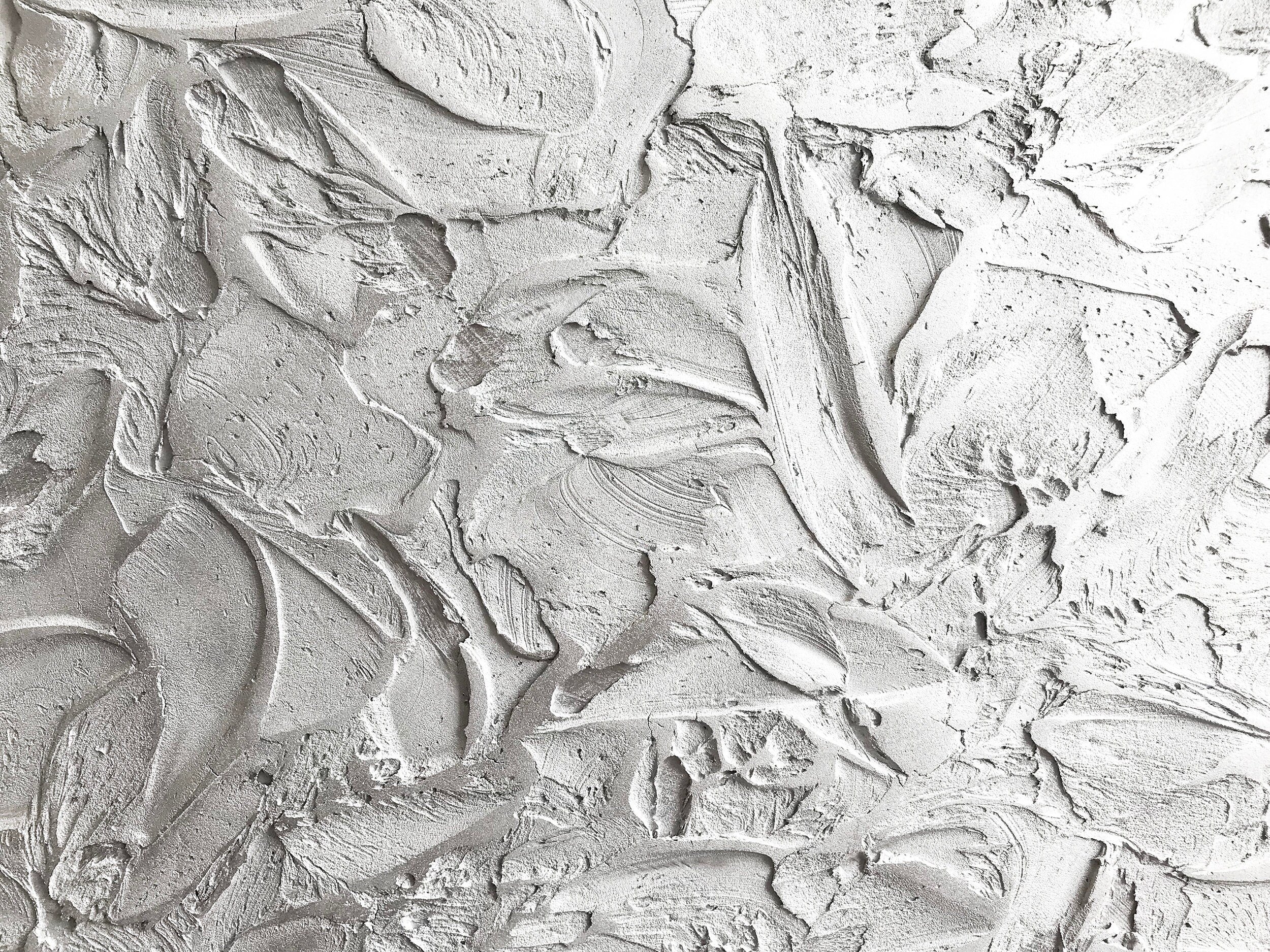 A close-up view of a textured white surface, reminiscent of textured art, featuring swirling and overlapping patterns that create an abstract, tactile surface.