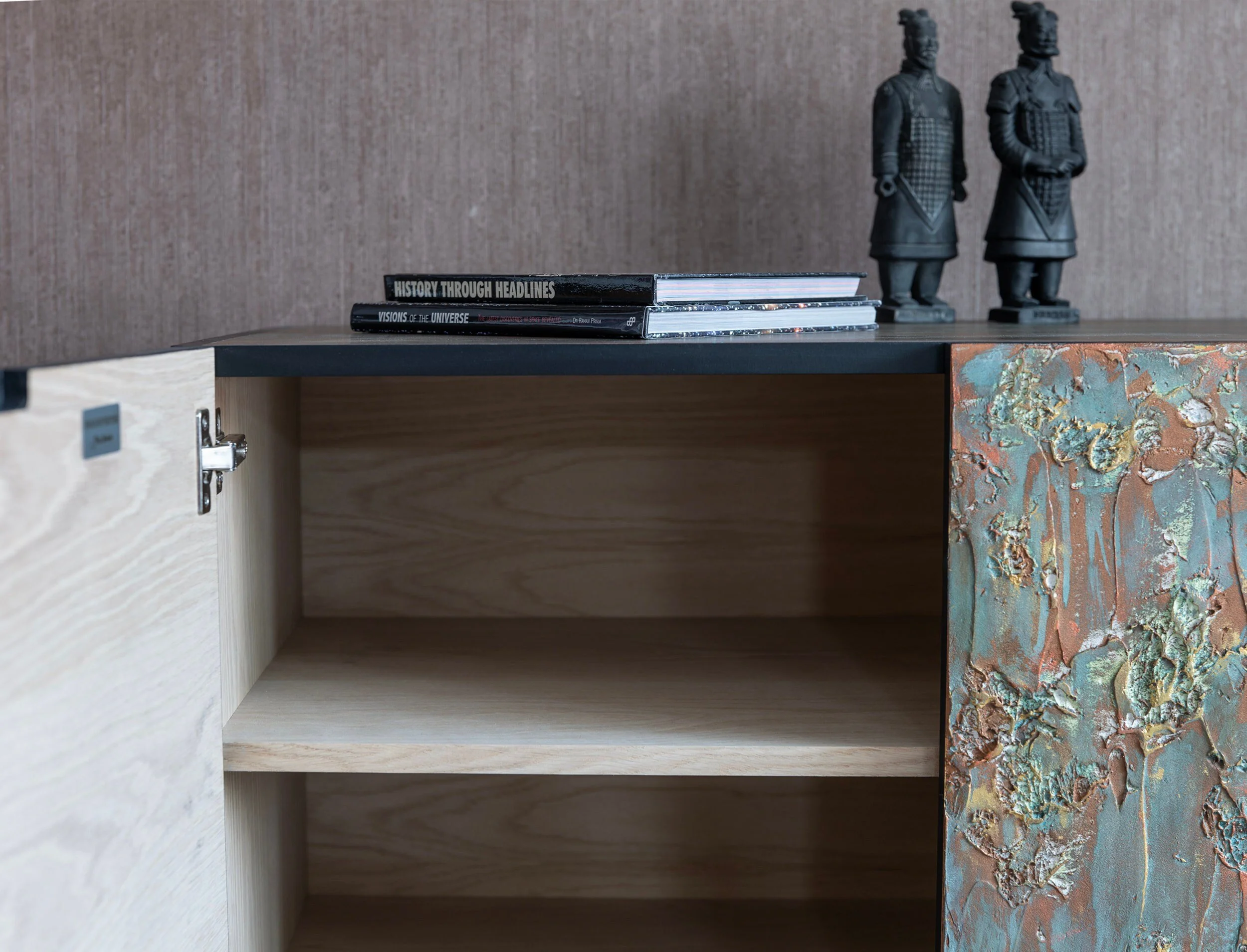 A wooden cabinet with an open door reveals empty shelves. This piece of bespoke furniture features a textured, earthy-colored side panel.