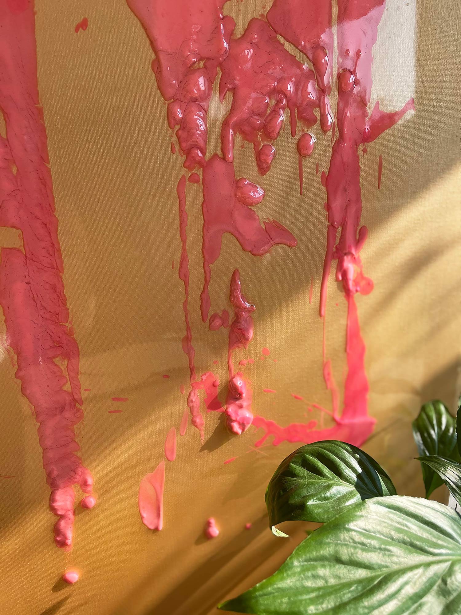Pink paint drips down a beige wall with a glossy texture, partially covering it in vibrant streaks.