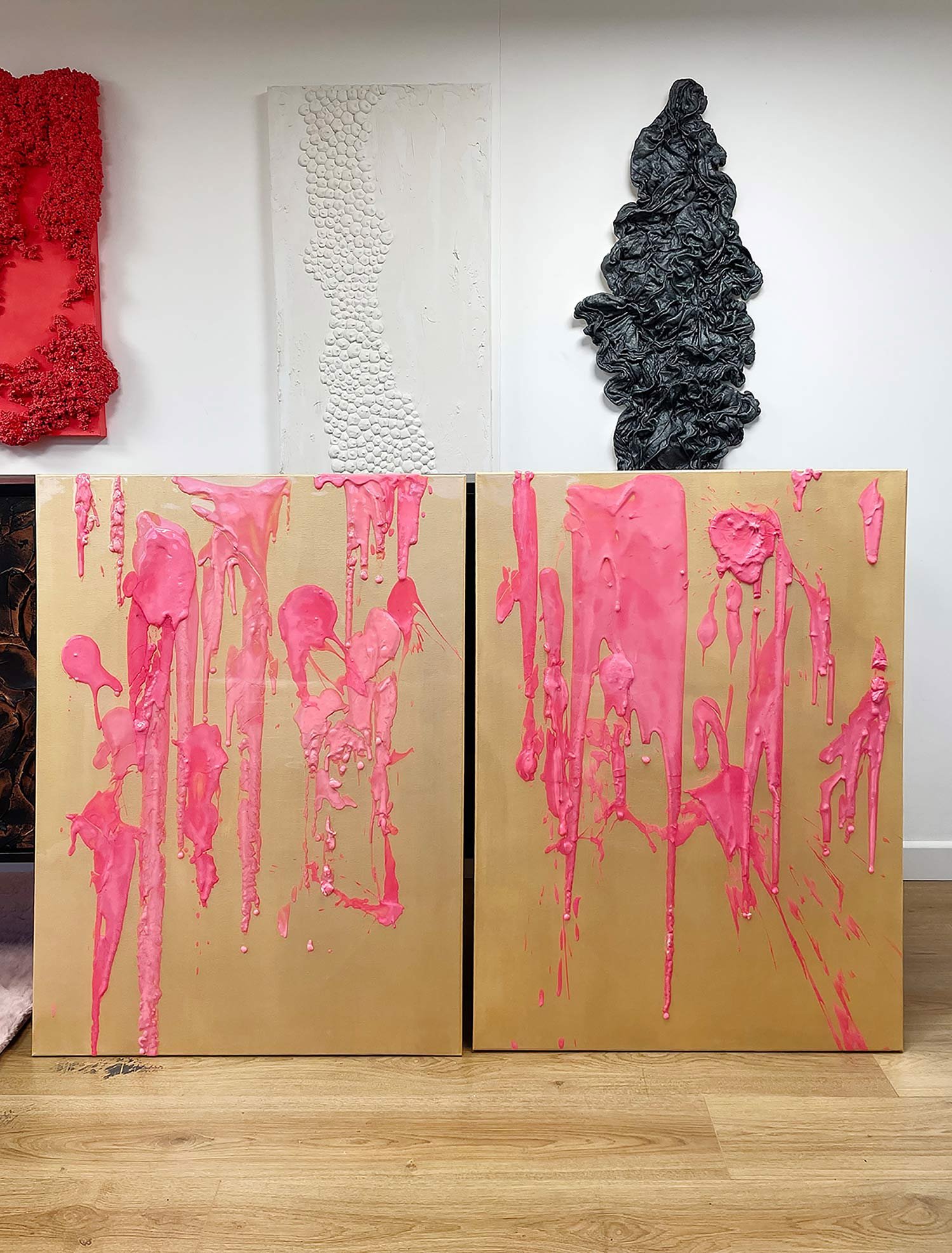 Two canvases with pink paint drips stand side by side.