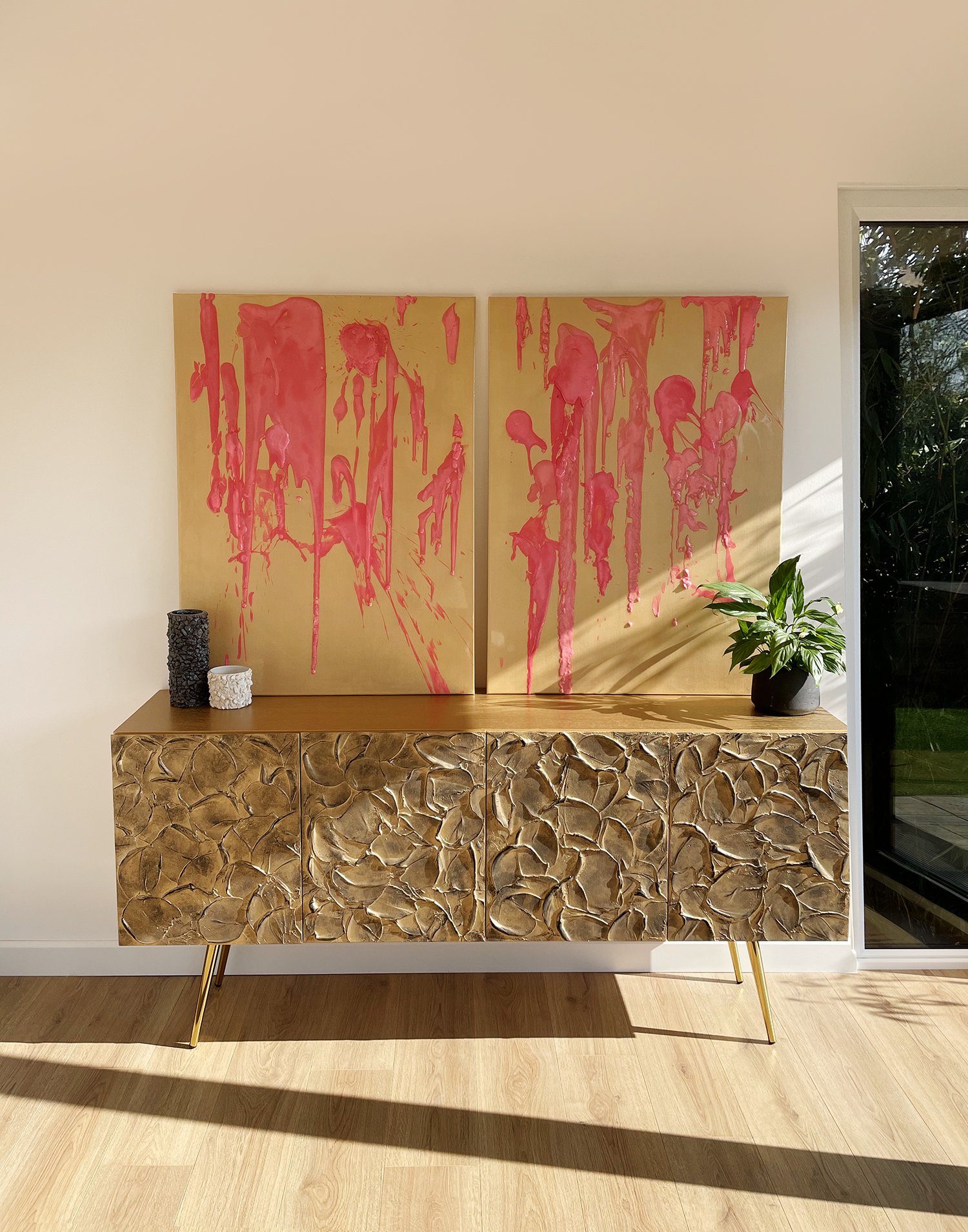 Two canvases with pink paint drips stand side by side.