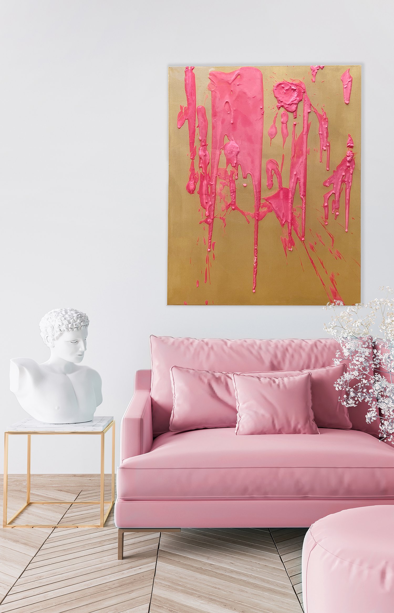 A living room with a pink sofa and cushions, a small gold and white side table with a marble bust, and a large abstract painting featuring pink drips on a gold background.
