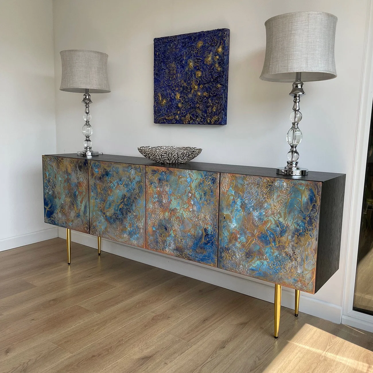 Angled view of the Midnight Galaxy 200cm sideboard, showcasing the seamless flow of 3D blue and gold abstract textures across the four doors and side panels, elevated on 30cm gold legs.