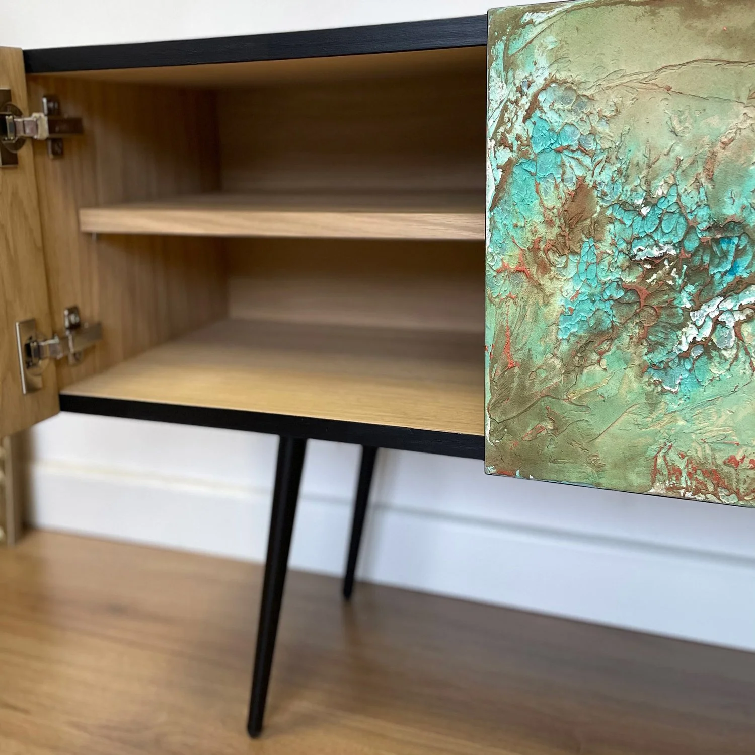 The open doors of the Nebula sideboard revealing the high-quality European oak veneer interior and adjustable shelving, contrasting with the vibrant green exterior.