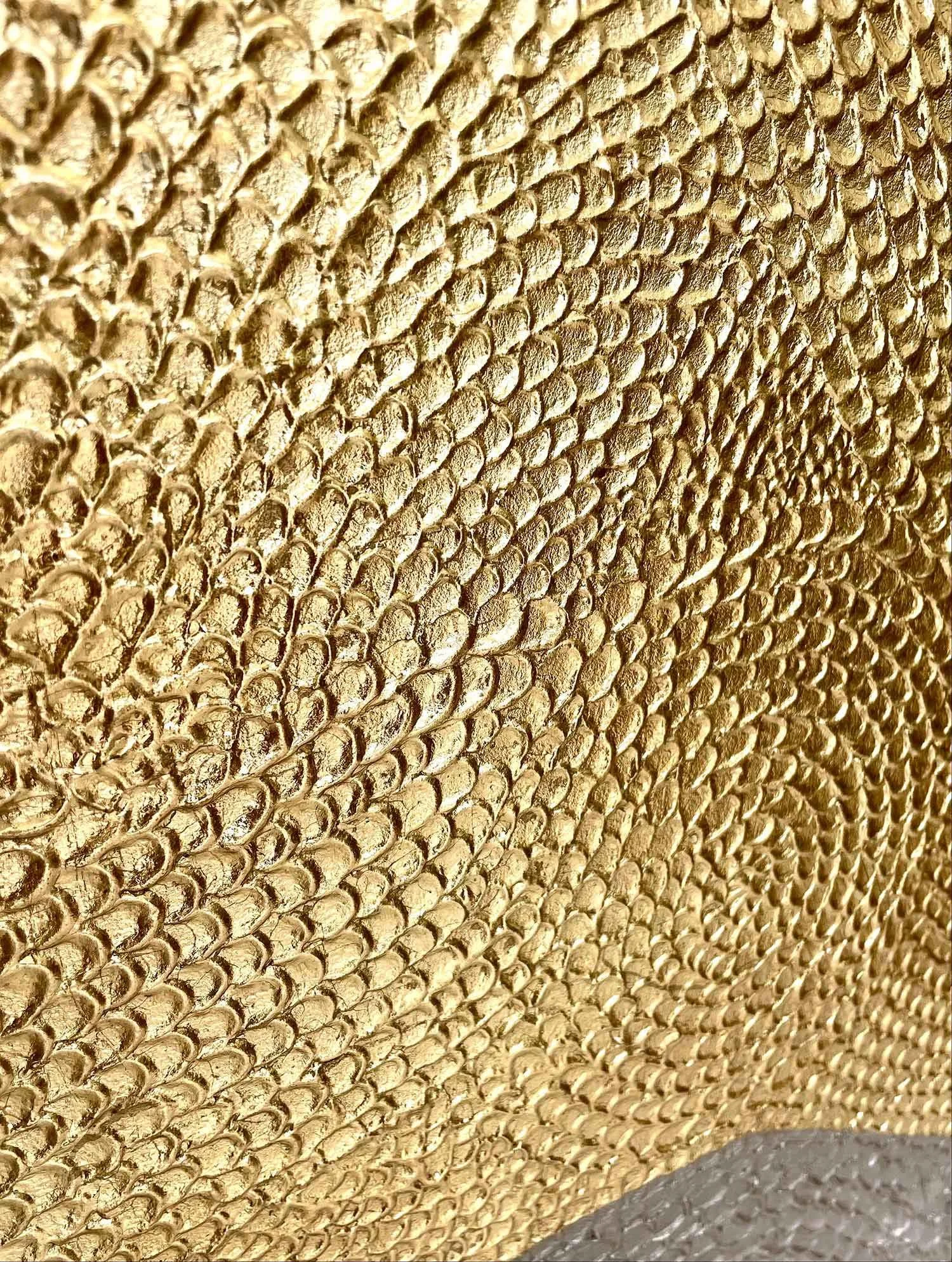 Close-up detail of the hand-sculpted botanical relief and antiqued gold leaf finish on a luxury sideboard door.