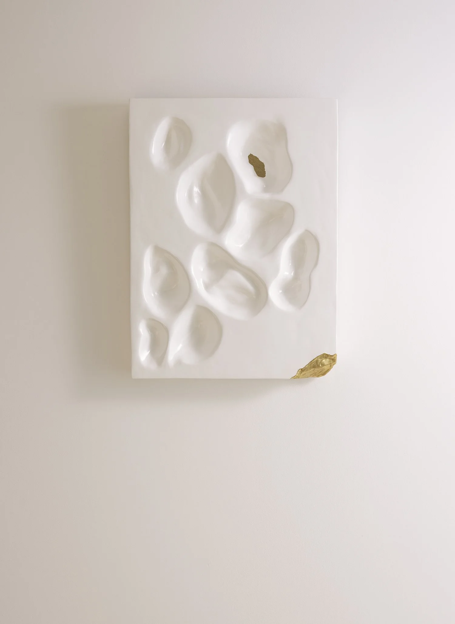 Modern high-relief sculpture featuring fluid white forms and delicate gold details, made from recycled materials.