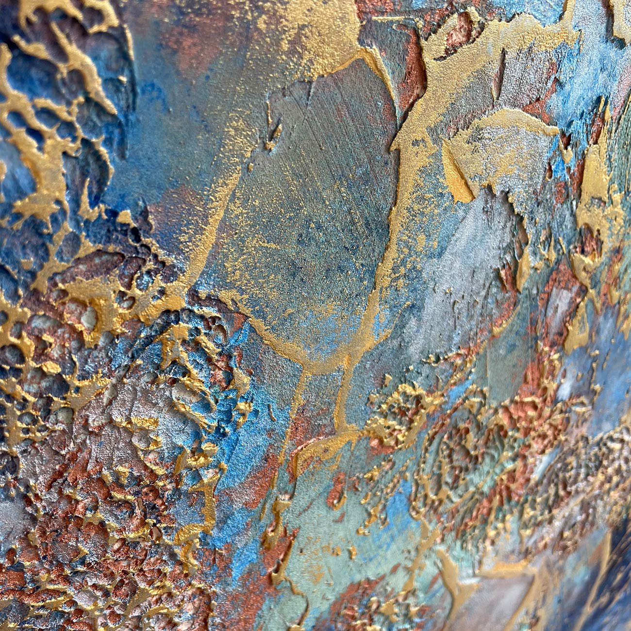 Extreme close-up detail of "Touch of Texture" artisan craftsmanship, showing the intricate, raised 3D peaks and valleys of blue pigment, oxidized copper tones, and shimmering gold leaf.