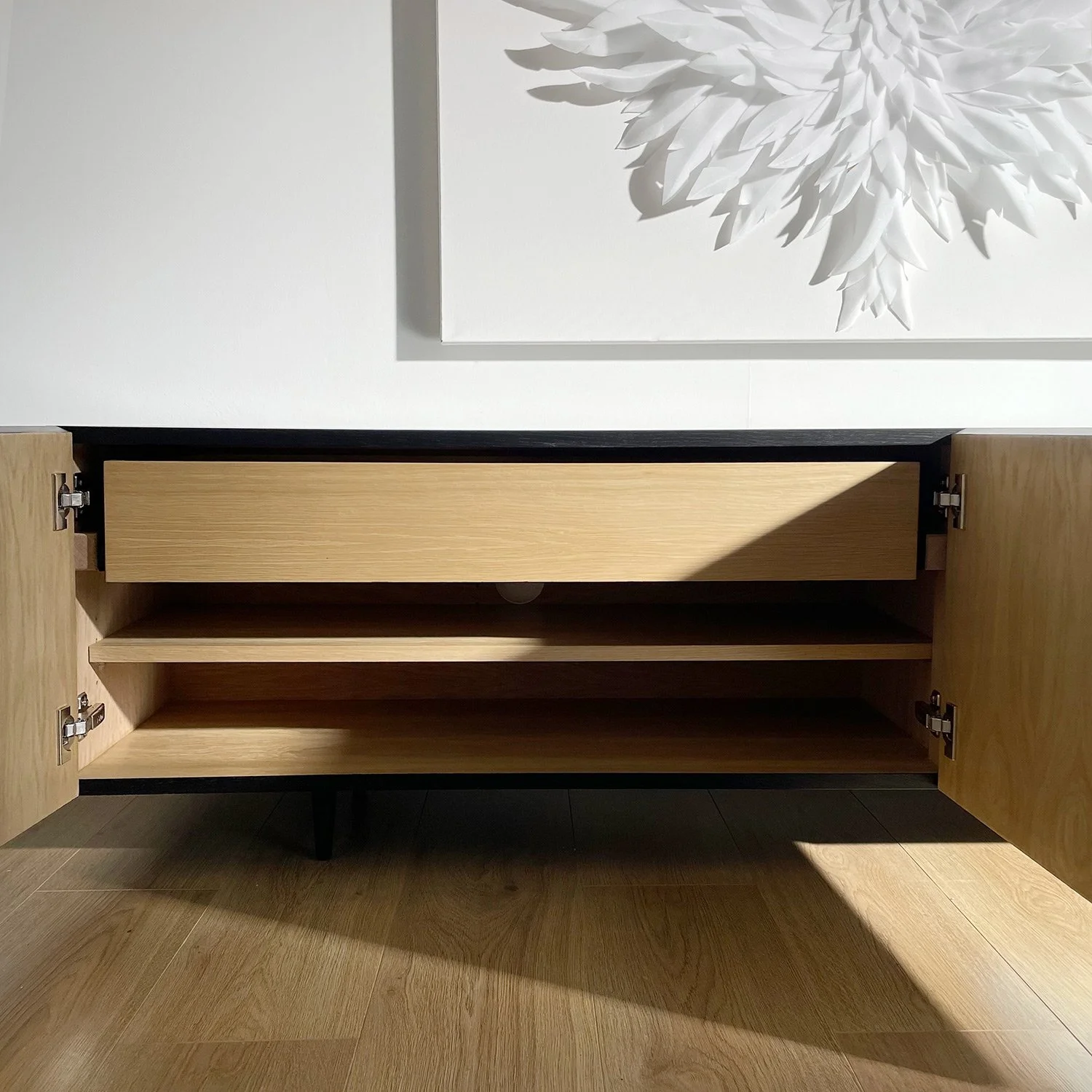 Interior view of spacious shelving inside bespoke textured sideboard, suitable for media or storage.