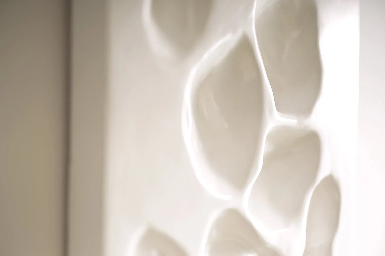 Close-up of the high-gloss, smooth, and deep organic recesses in the white recycled plastic art.